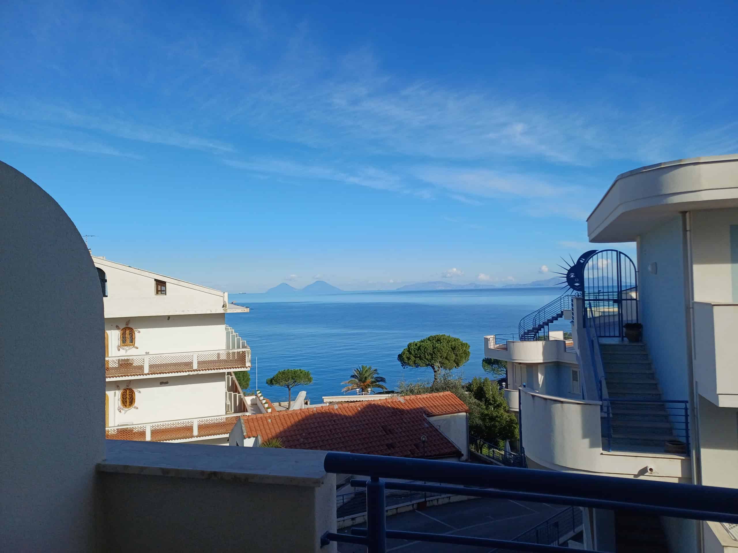 Balcone con vista mare e isole, case moderne e terrazza soleggiata, in zona residenziale vicino al mare, con paesaggio marino e cielo azzurro, ideale per vacanze o soggiorni rilassanti in Italia.