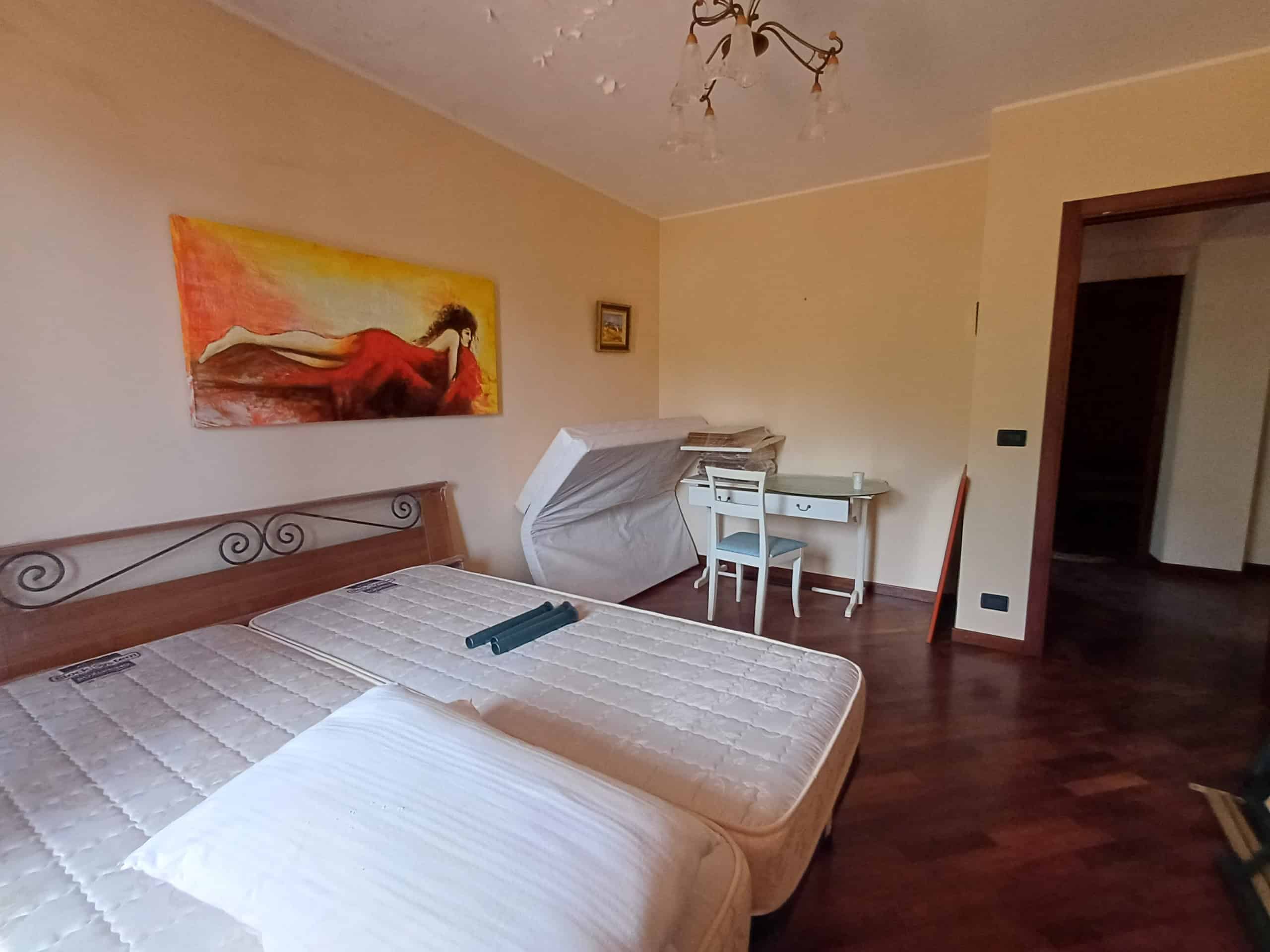 Interno di una camera da letto con due letti, scrivania e decorazioni colorate, in una casa in vendita a Ficarra, Me.