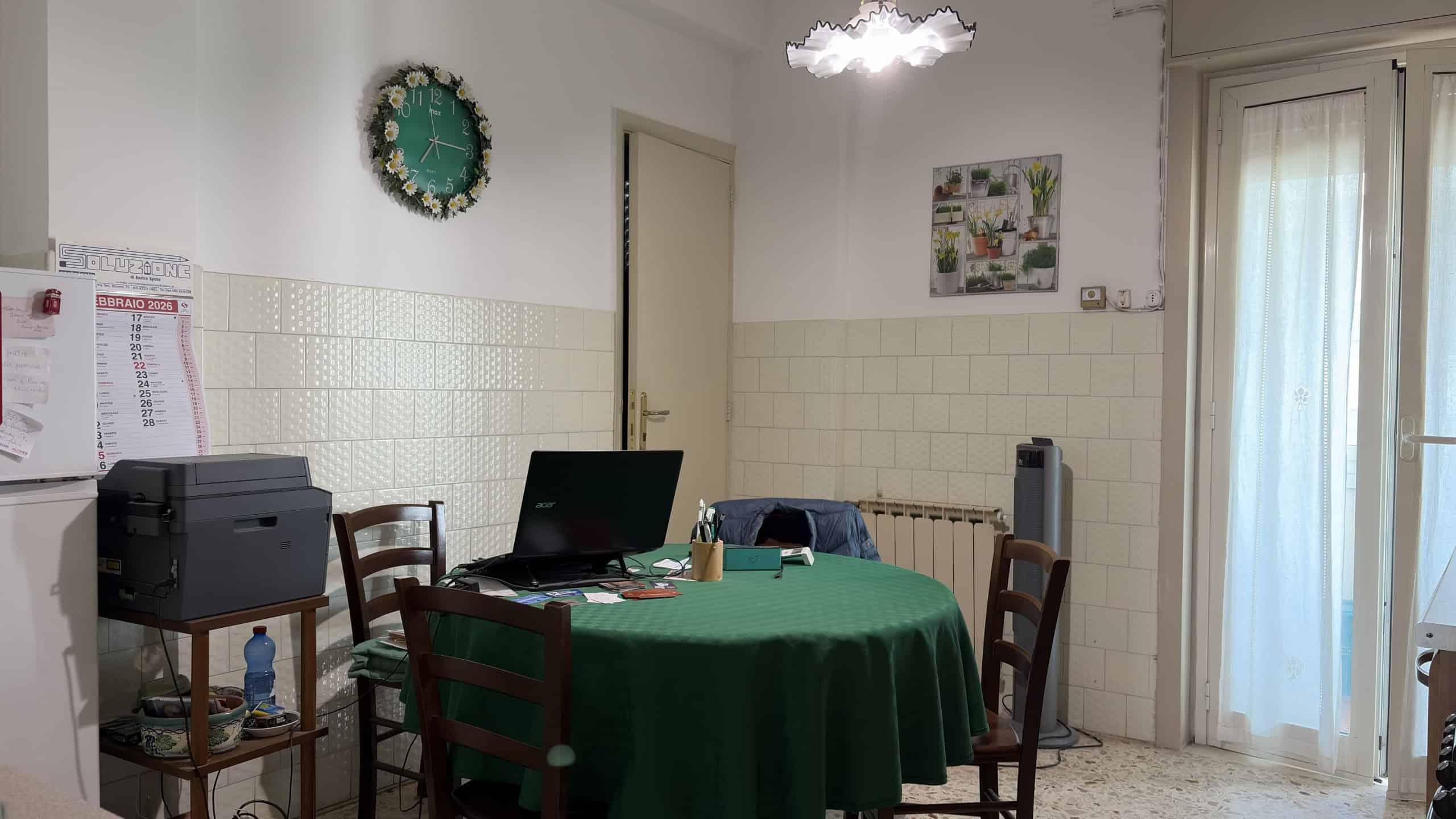 Pannello di controllo e scrivania in un ufficio domestico con sedia, computer e stampante, ambiente luminoso e accogliente, ideale per lavoro o studio a casa.