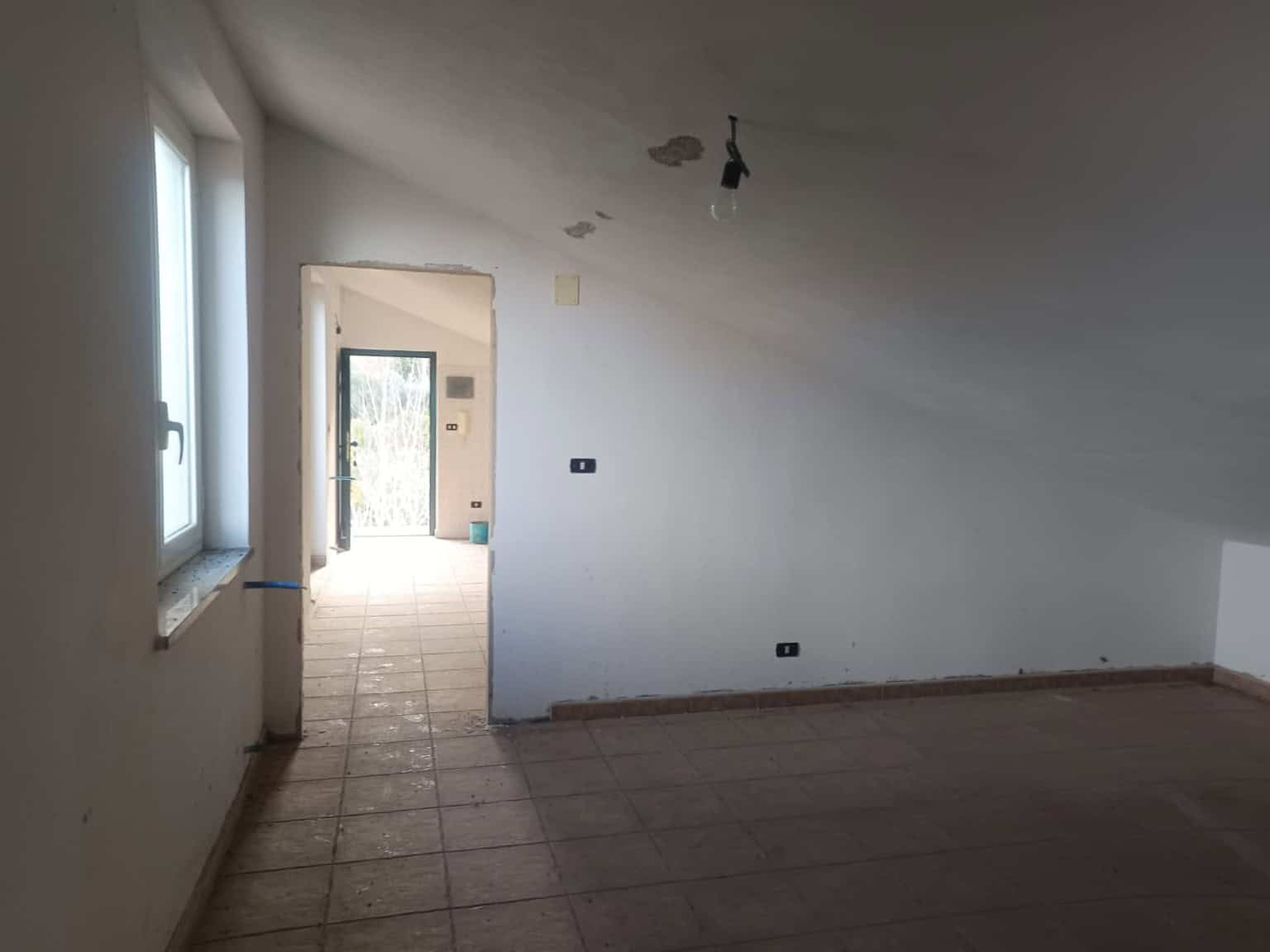 Interno di un appartamento in fase di ristrutturazione con pareti bianche e pavimento in piastrelle, pronto per essere arredato e personalizzato.