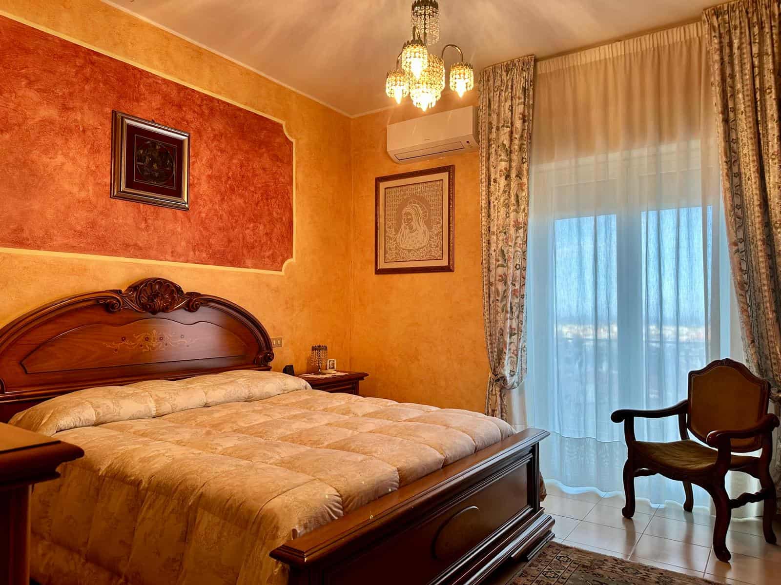 Camera da letto elegante con arredi classici, pareti colorate e tende leggere, ideale per soggiorni confortevoli e raffinati.