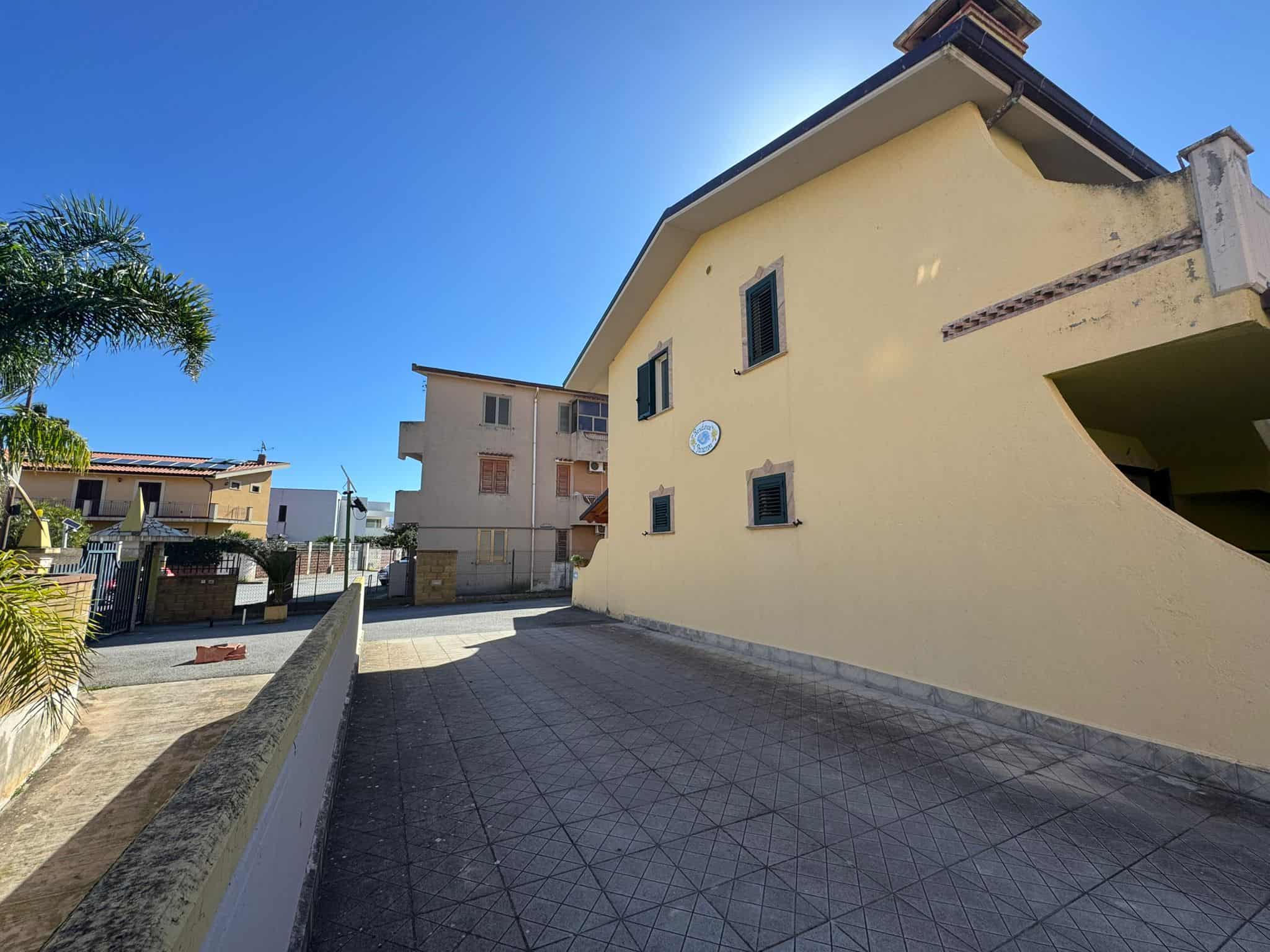 Edificio residenziale moderno con facciata gialla e ampio spazio esterno, situato in zona tranquilla e ben servita.