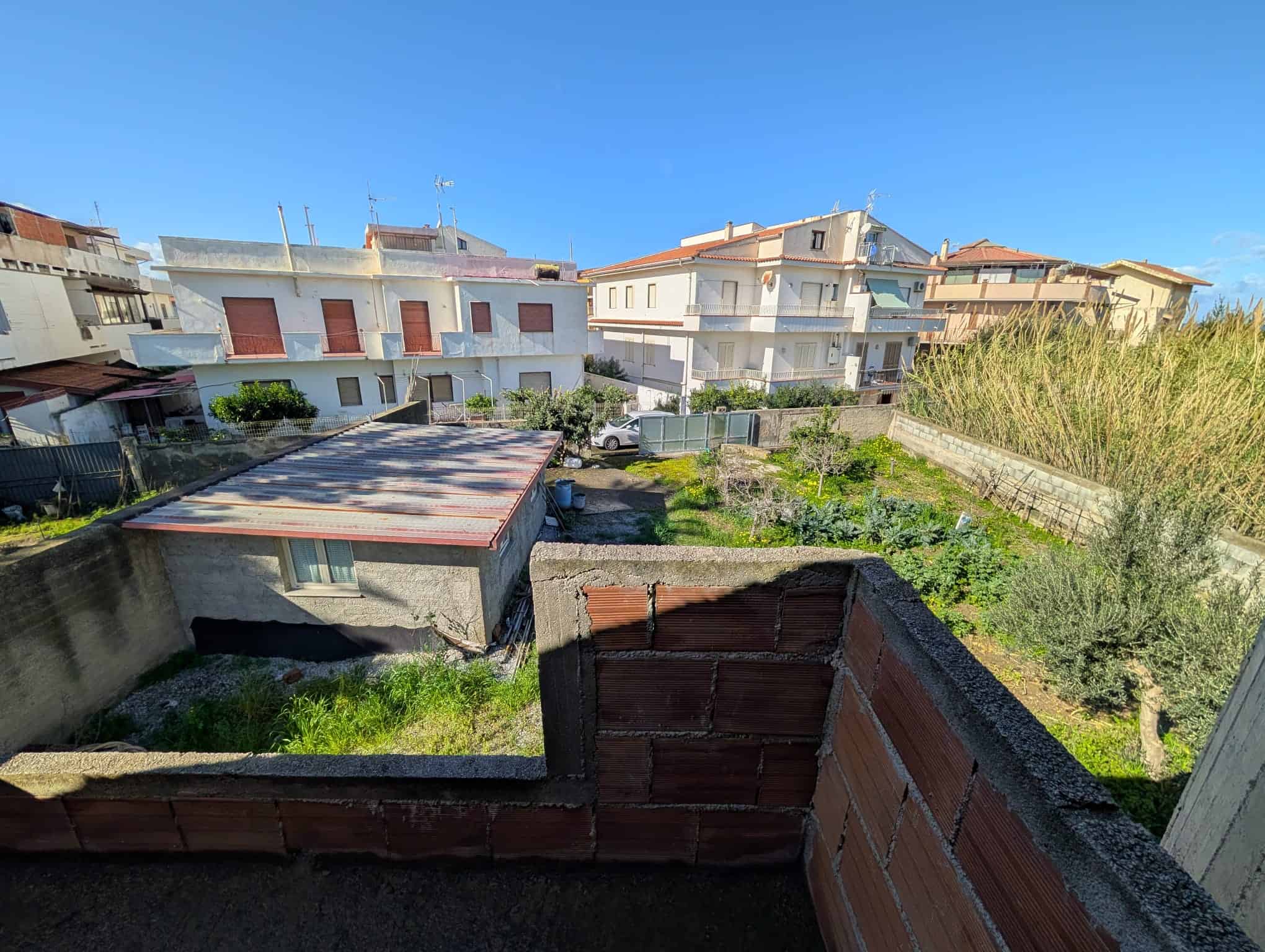 Vista di un cortile residenziale con case e giardini, cielo sereno, in un quartiere urbano.