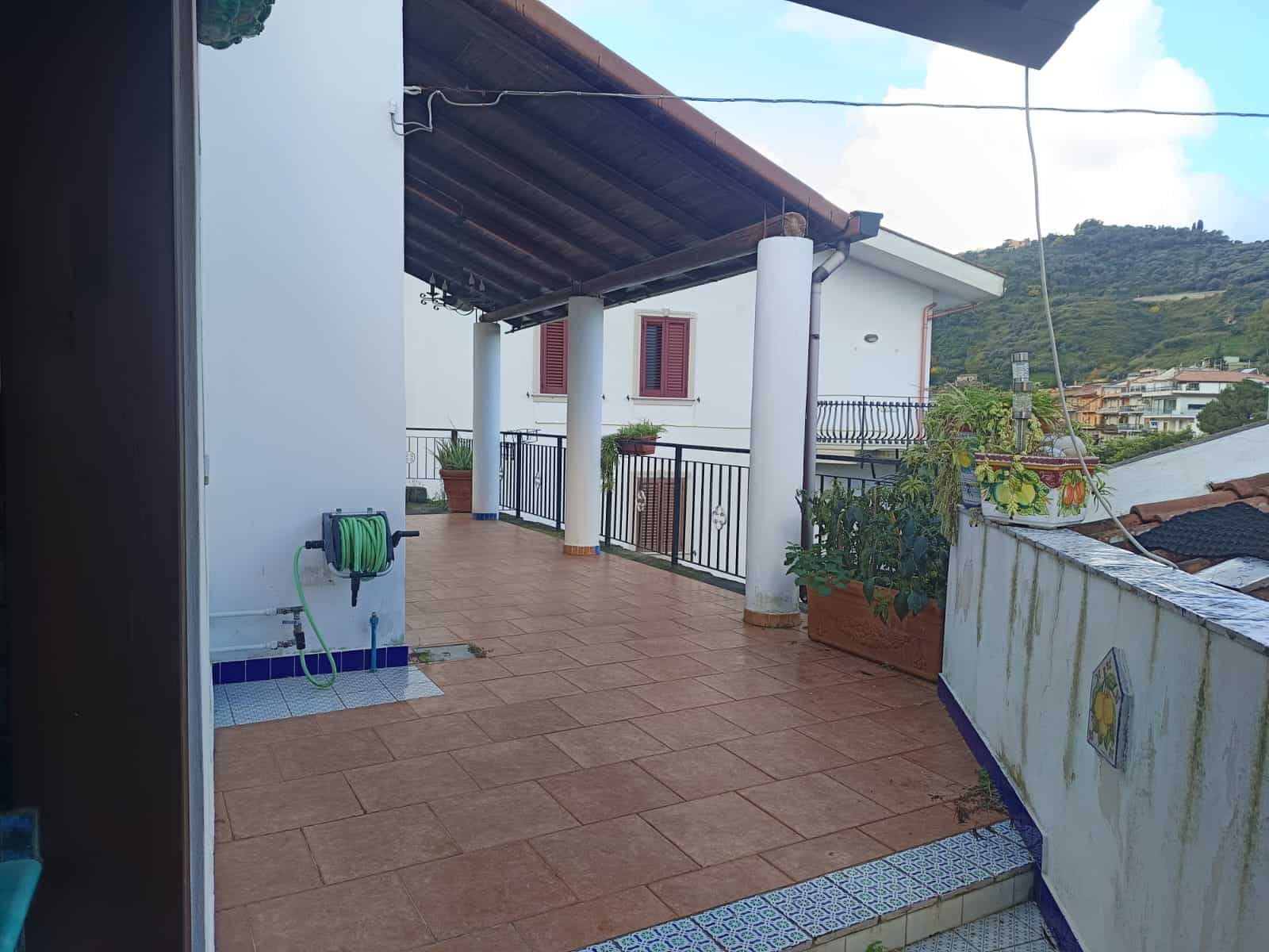 Balcone panoramico di una casa in stile mediterraneo con vista sulle colline, pavimentazione in gres, piante ornamentali e area relax all'aperto, ideale per vivere momenti di convivialità e godere del.