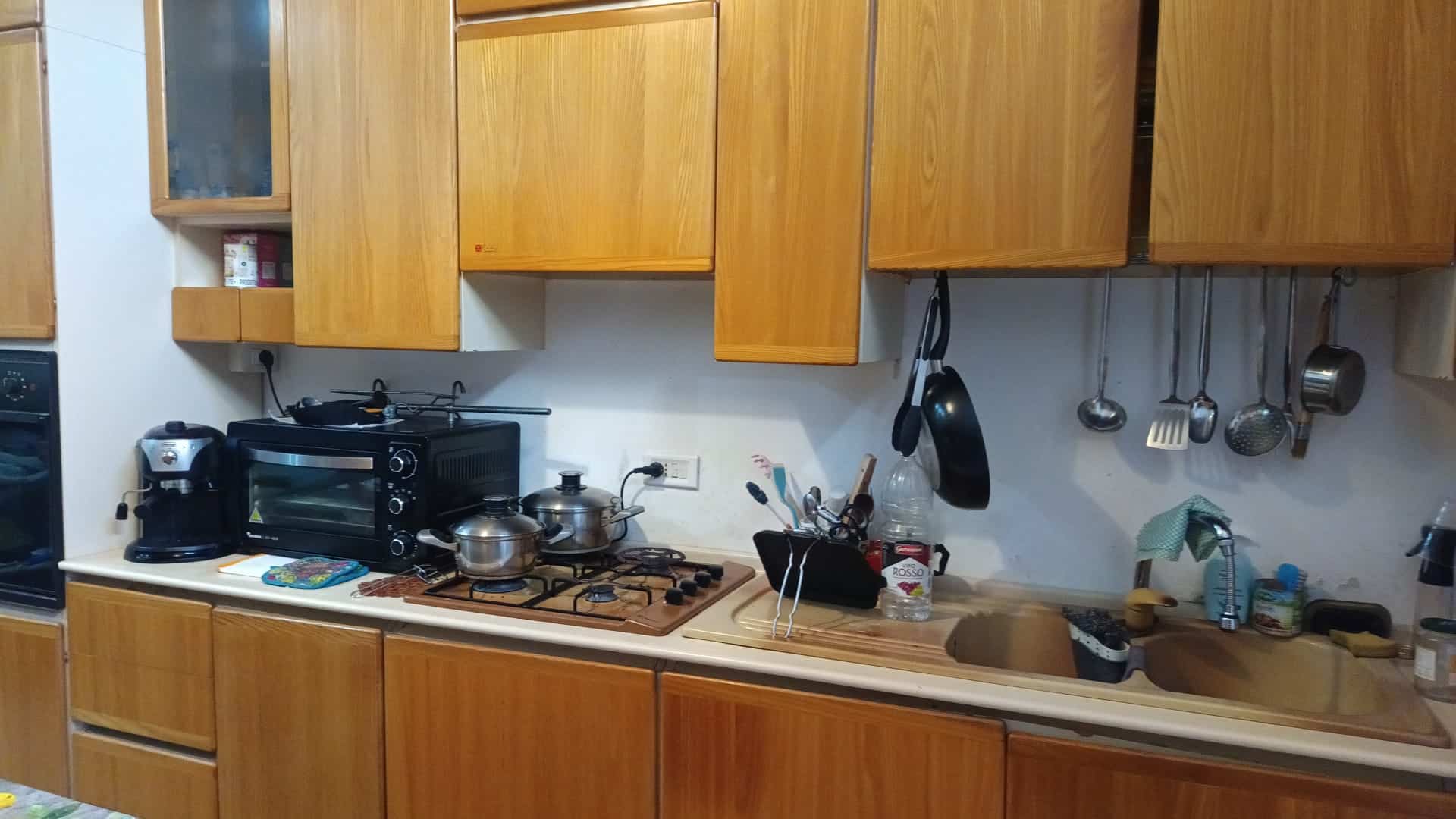 Lavastoviglie e utensili da cucina in una moderna cucina in legno con piano di lavoro in laminato chiaro.