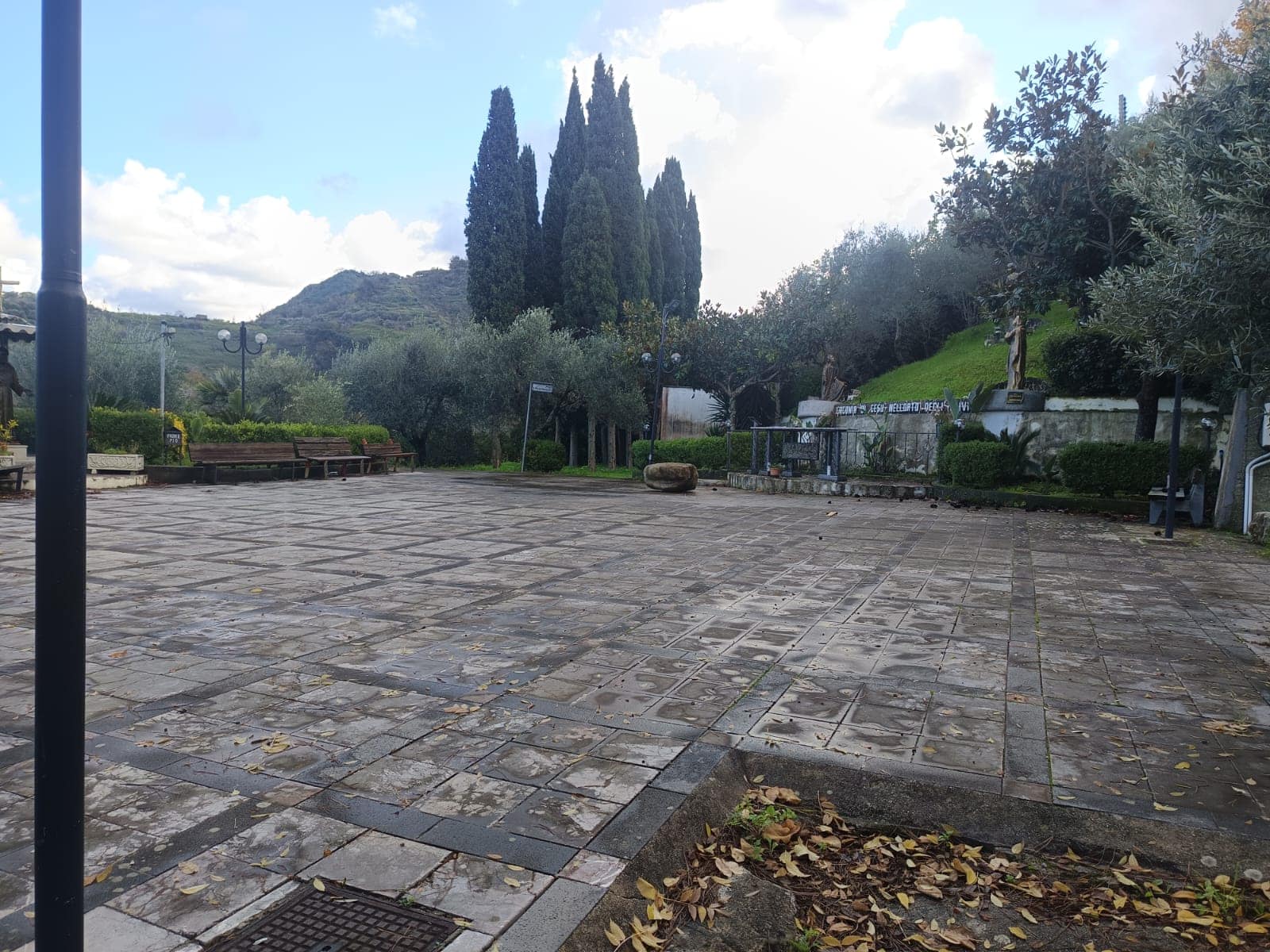 Pavimentazione in pietra naturale in un parco pubblico con alberi e panchine, ambiente tranquillo e ben curato, ideale per passeggiate e relax all'aperto.