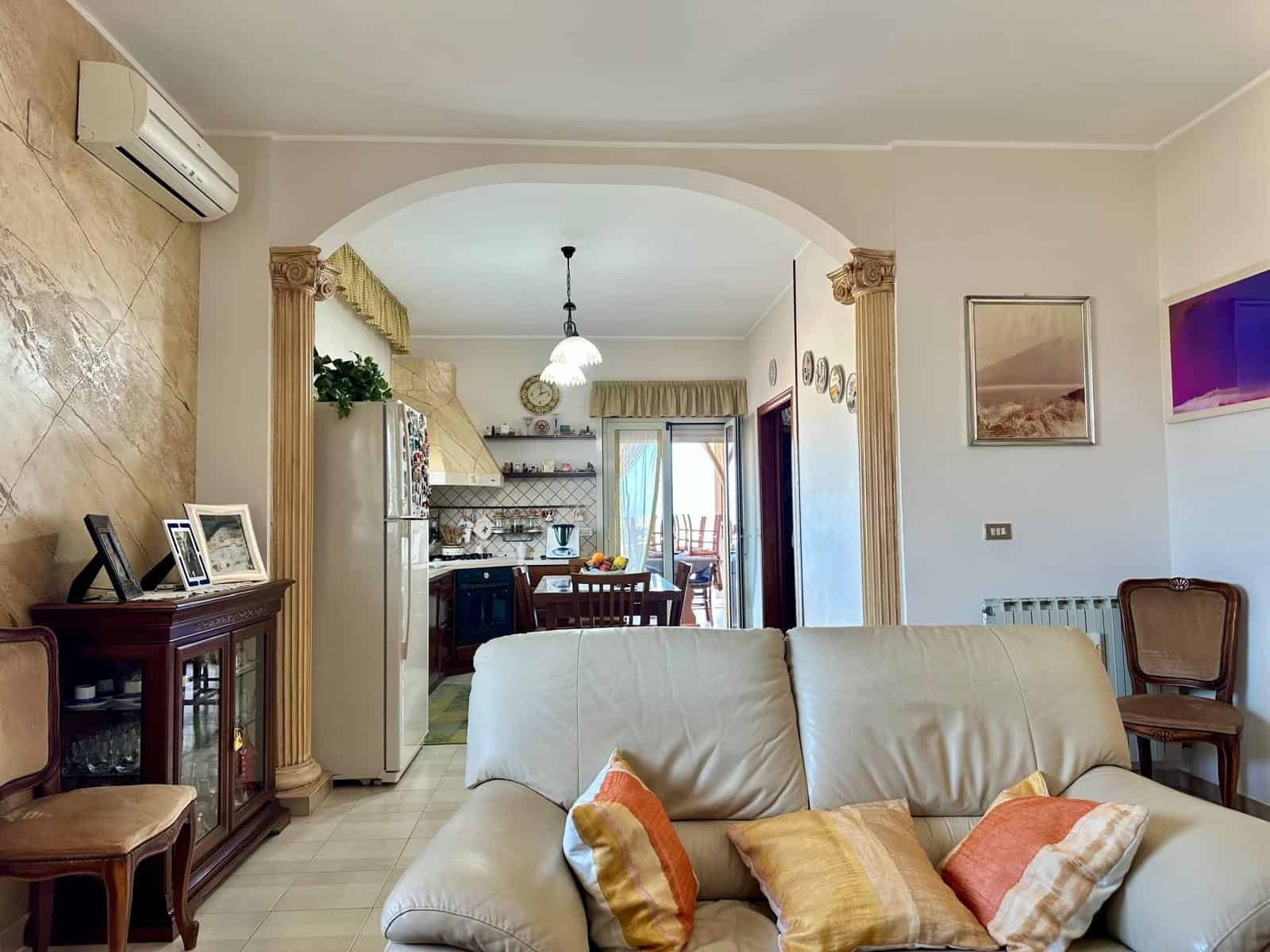 Ampio soggiorno con zona pranzo e cucina a vista, arredamento accogliente e luminoso, dettagli decorativi eleganti, ideale per vivere momenti di relax e convivialità in casa.