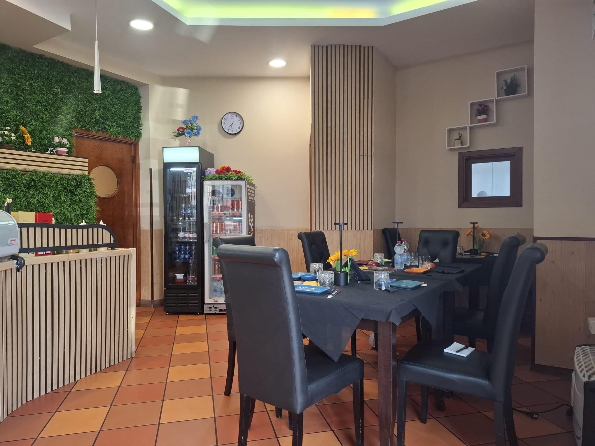Sedie nere in sala da pranzo con tavolo apparecchiato, ambiente accogliente e moderno con decorazioni floreali e pareti decorate, ideale per pranzi e cene conviviali.