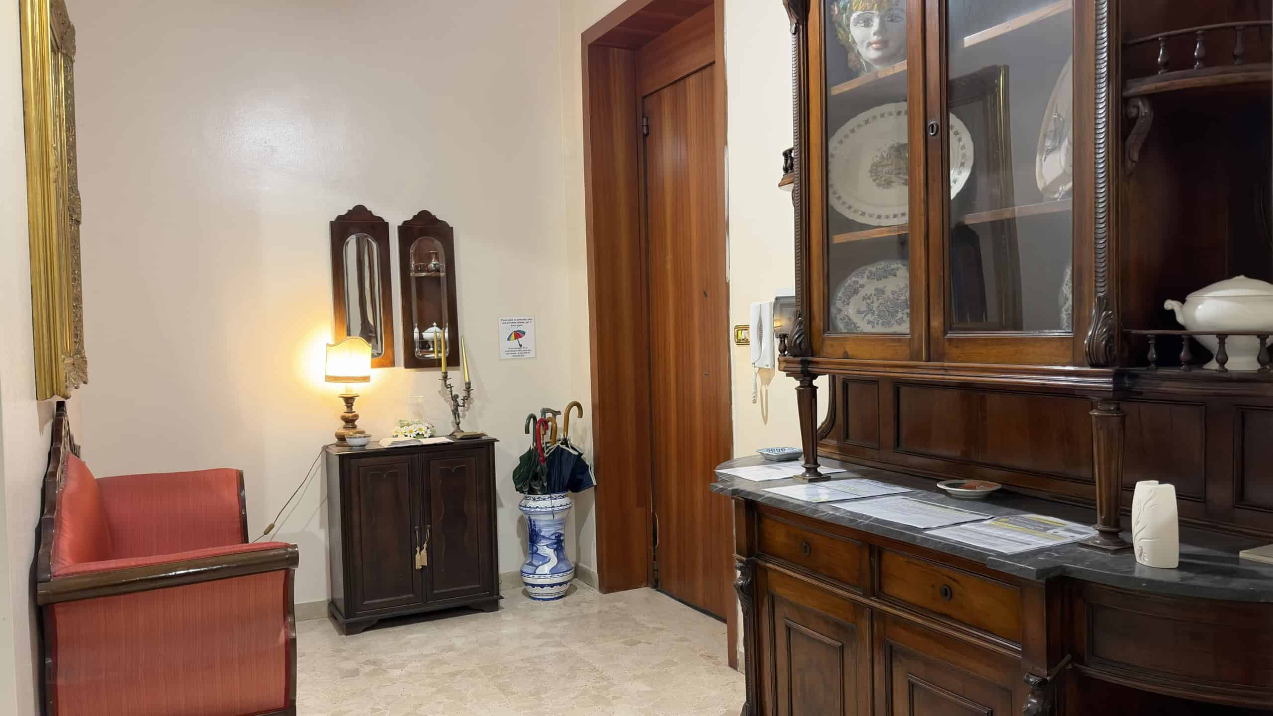 Elegante soggiorno con mobili in legno, lampada da tavolo e decorazioni classiche, ideale per ambienti accoglienti e raffinati. Perfetto esempio di arredamento tradizionale italiano.