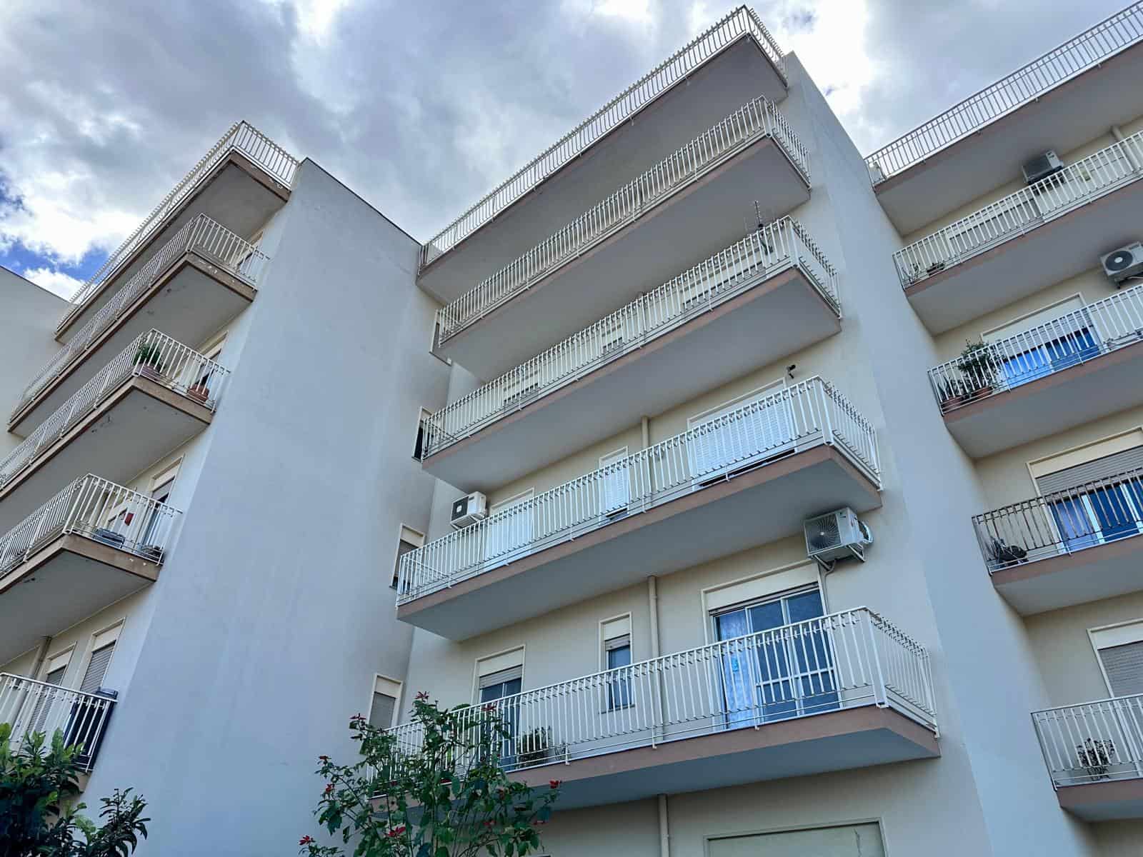 Appartamento moderno con balconi spaziosi in edificio residenziale a più piani, vista panoramica e facciata bianca, ideale per investimento o abitazione principale in zona urbana.
