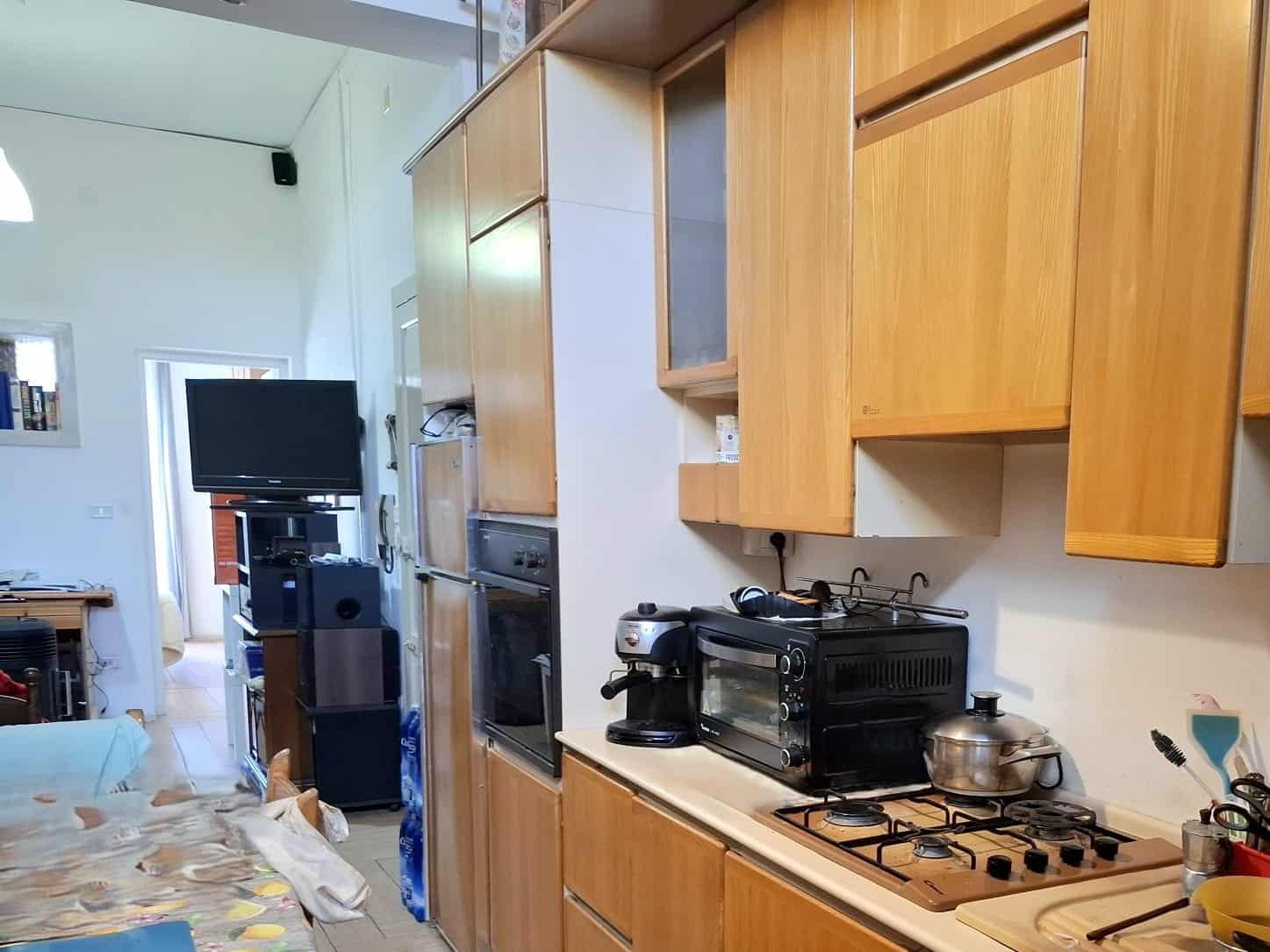 Pentole e utensili da cucina su piano di lavoro in una cucina moderna con mobili in legno chiaro.