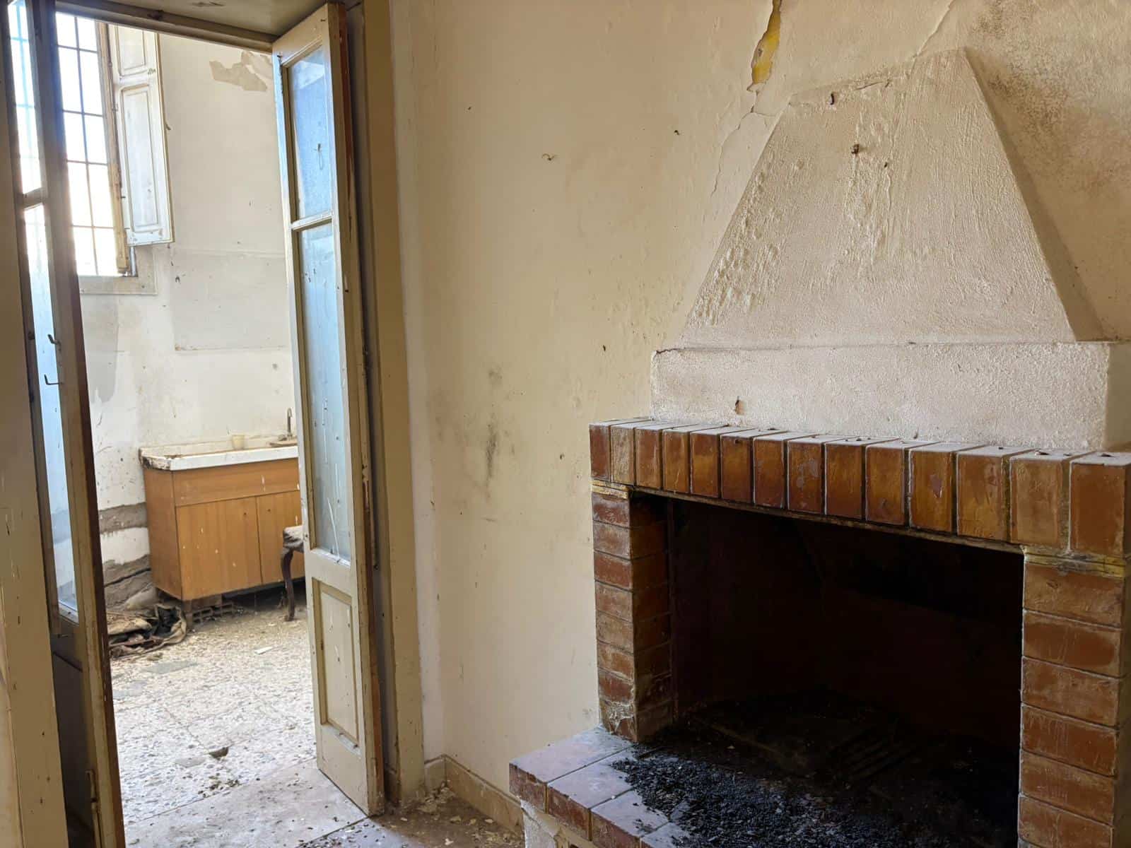 Il camino in mattoni in un ambiente rustico e accogliente, con pareti in pietra e una finestra che lascia entrare luce naturale, ideale per creare un'atmosfera calda e invitante in casa.