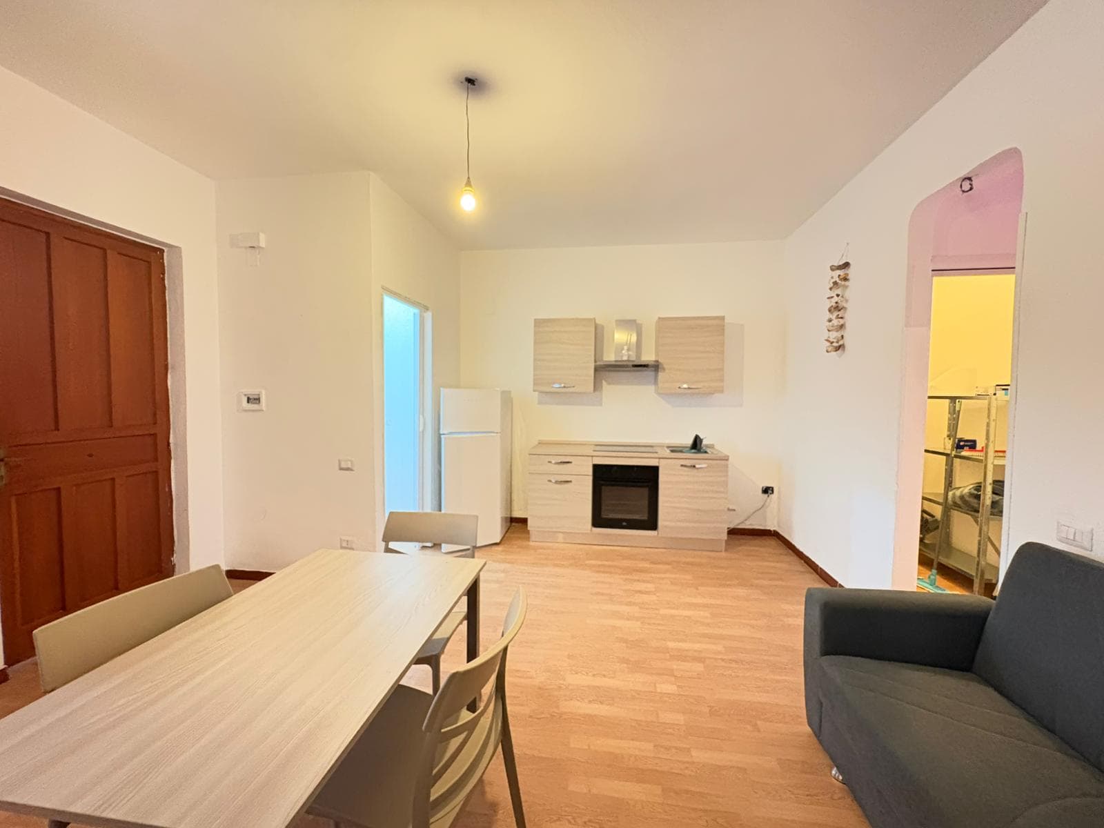 Ampia zona living con cucina moderna e soggiorno con divano, ambiente luminoso e accogliente, ideale per famiglie e coppie, perfetta per vivere momenti di relax e convivialità.