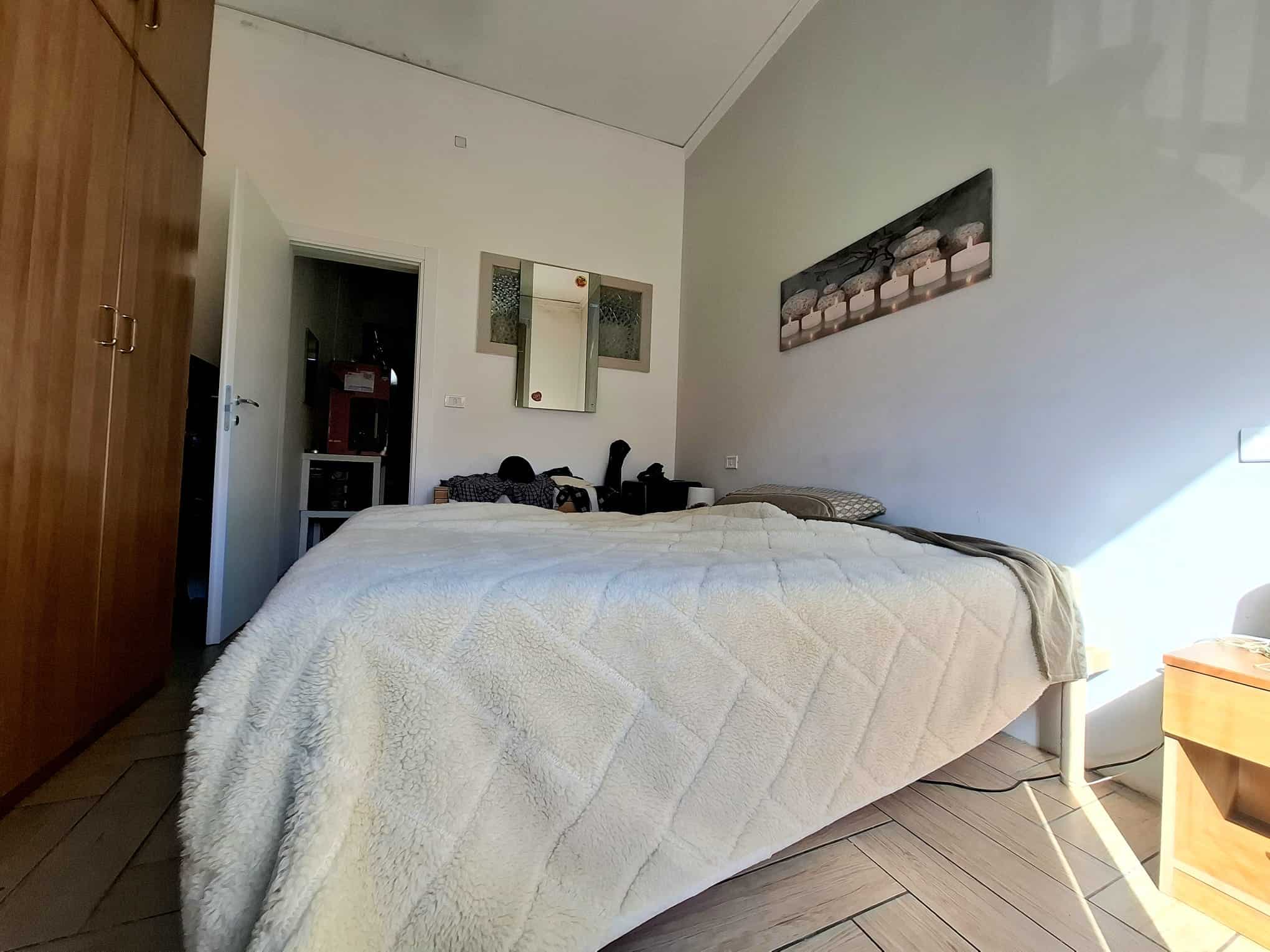 Ampia camera da letto con letto matrimoniale, armadio in legno e decorazioni moderne sulle pareti, ambiente luminoso e accogliente, ideale per soggiorni confortevoli.