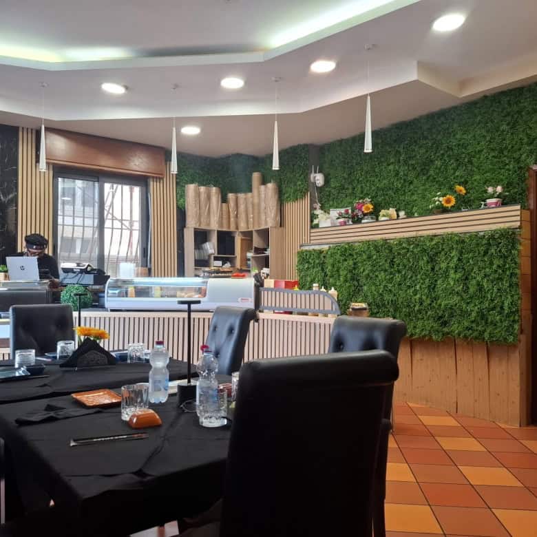 Tavolo da pranzo elegante in un ristorante con decor verde e arredi moderni, illuminazione soffusa e ambiente accogliente, ideale per cene conviviali e incontri di lavoro.