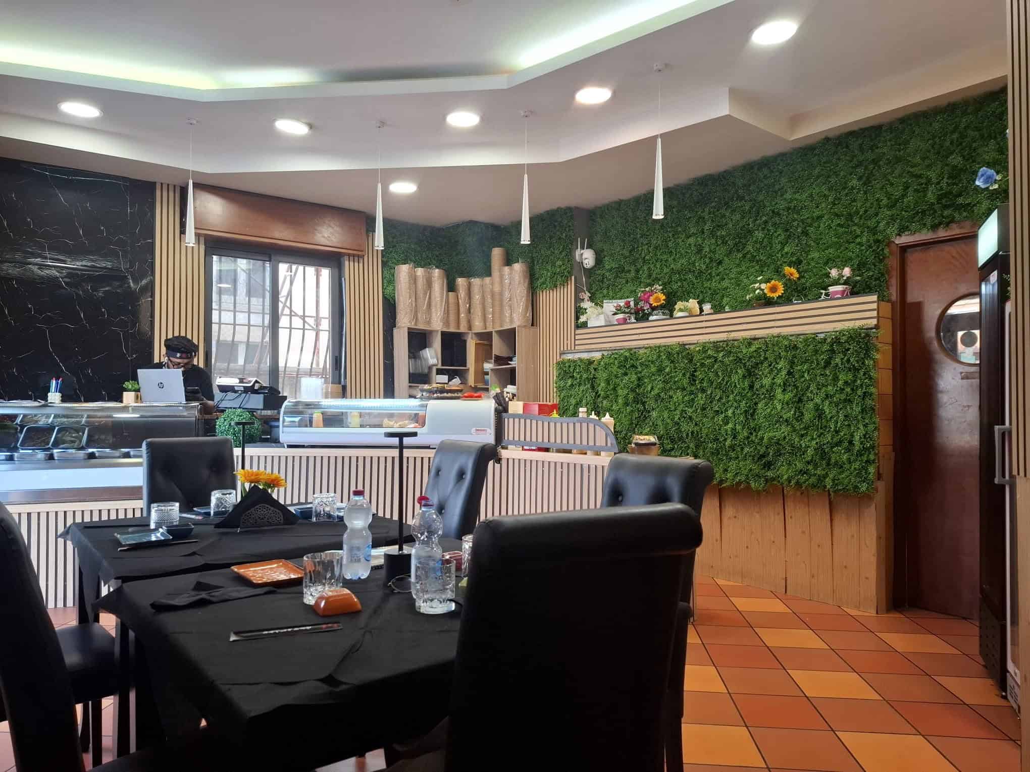Tavolo da pranzo elegante in un ristorante con decor verde e arredi moderni, illuminazione soffusa e ambiente accogliente, ideale per cene conviviali e incontri di lavoro.