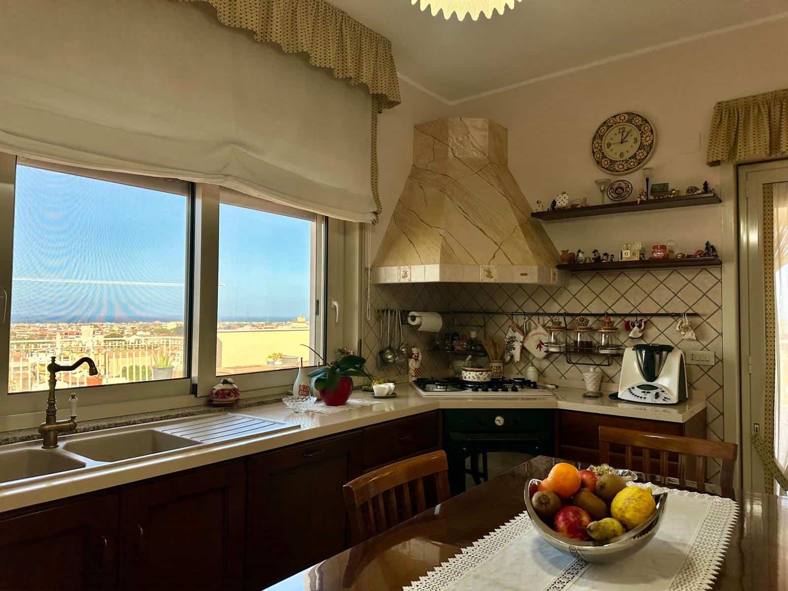 Cucina abitabile con finestra panoramica, mobili in legno e elettrodomestici moderni, ambiente accogliente e luminoso.