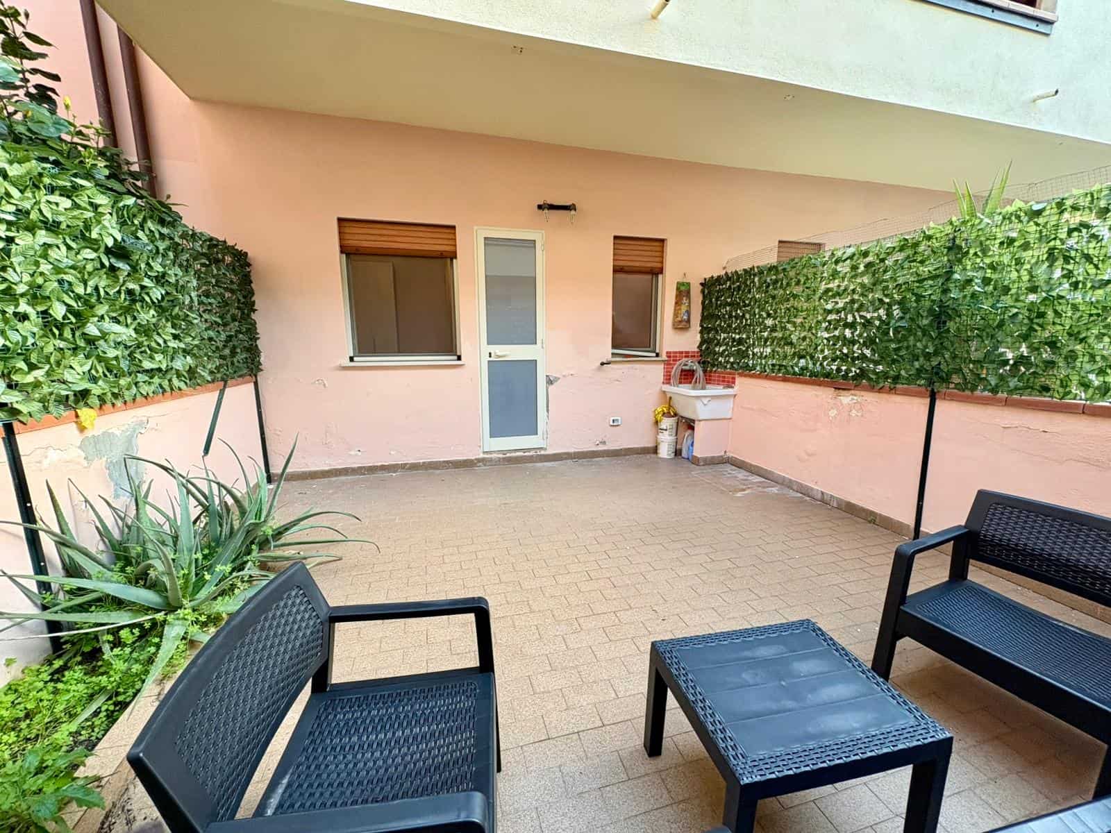 Spazio esterno privato con panchine e piante verdi, ideale per relax e socializzare in un ambiente tranquillo e ben curato.
