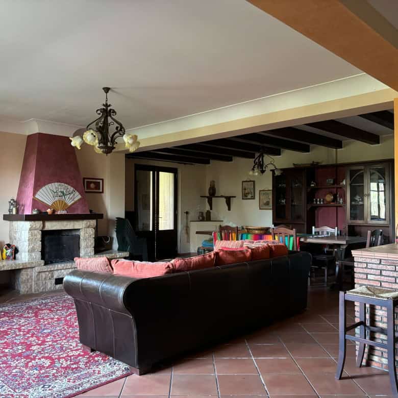 Ampia zona living con camino in pietra, divani confortevoli e arredi eleganti in stile rustico, ideale per relax e incontri familiari in un ambiente accogliente e luminoso.