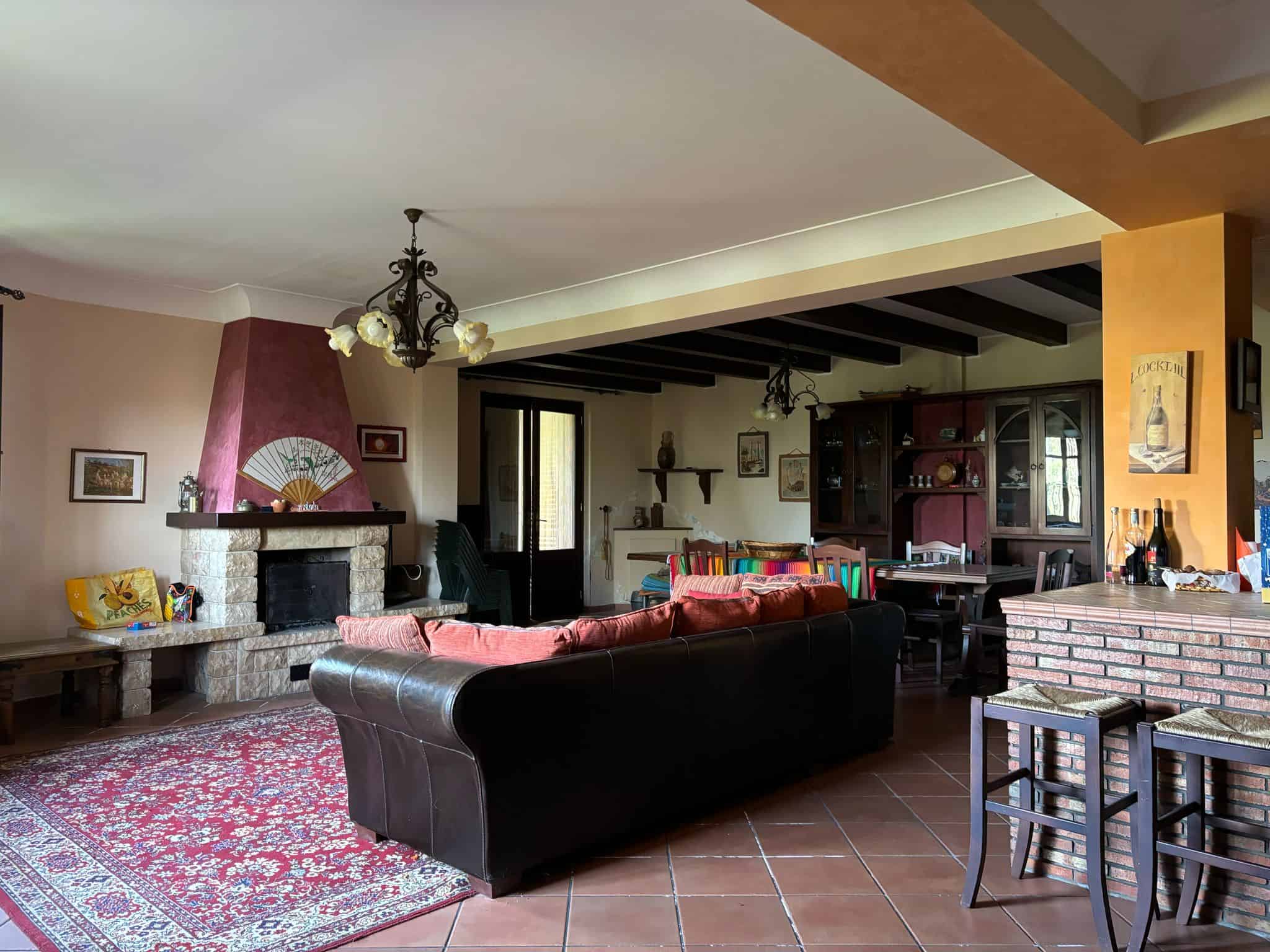 Ampia zona living con camino in pietra, divani confortevoli e arredi eleganti in stile rustico, ideale per relax e incontri familiari in un ambiente accogliente e luminoso.