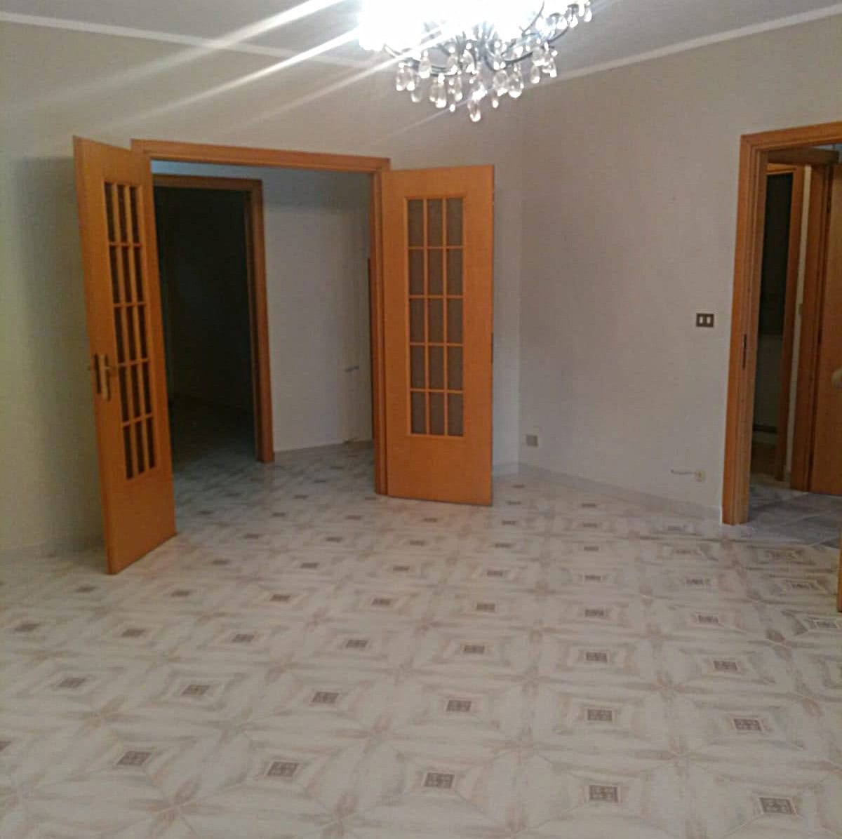 Interno spazioso con porte in legno e pavimento in piastrelle decorative, ideale per ristrutturazioni e arredi moderni in case e appartamenti in Italia.