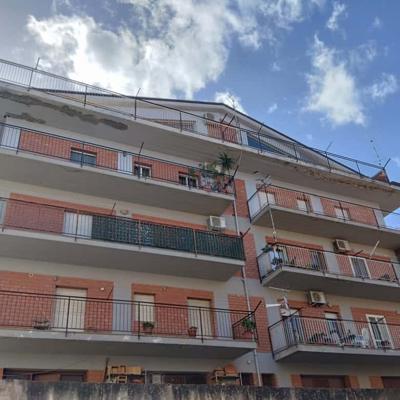 Appartamento residenziale con balconi e aria condizionata, edificio moderno in zona urbana, vista panoramica sul cielo e sulle nuvole, struttura in mattoni e cemento, ideale per vivere in città.
