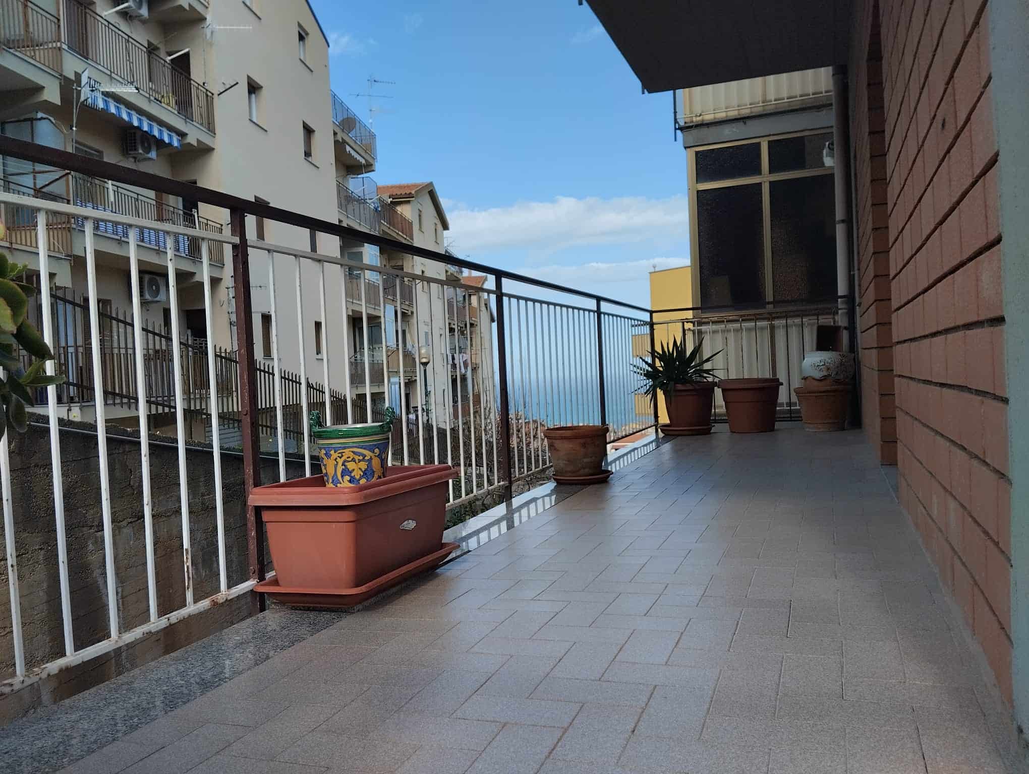 Vaso di fiori su balcone di un appartamento in città con vista sul mare, ambiente urbano e spazi esterni abitativi, ideale per annunci immobiliari e promozione di immobili residenziali in Italia.