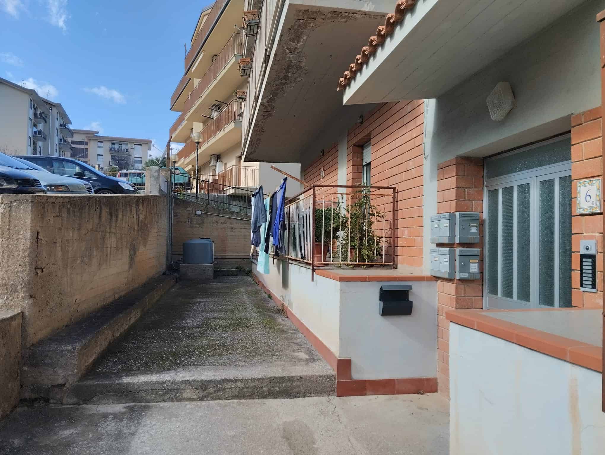 Lavatrice e vestiti stesi ad asciugare sul balcone di un appartamento in un complesso residenziale.