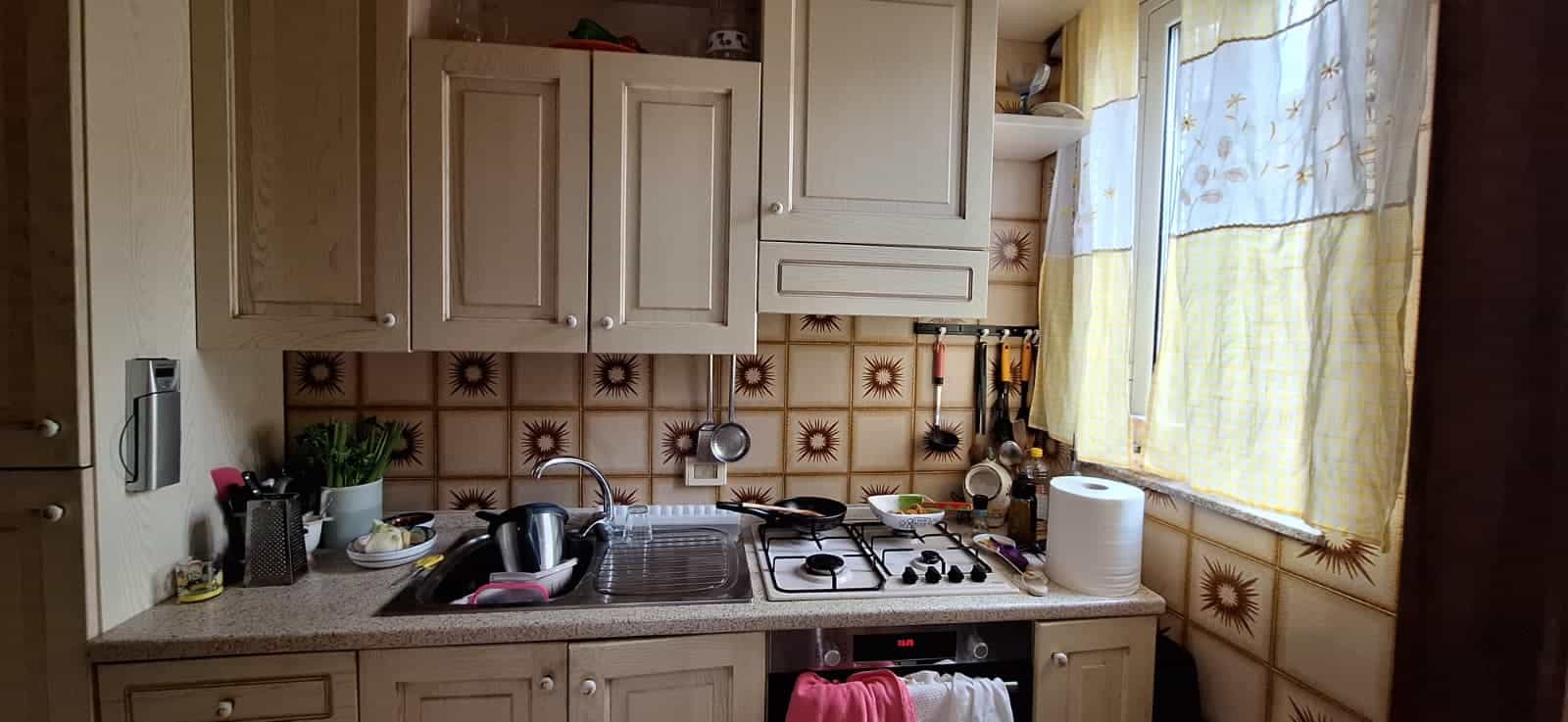 Pannello cucina con lavello, fornelli e utensili, ambiente domestico funzionale e accogliente.