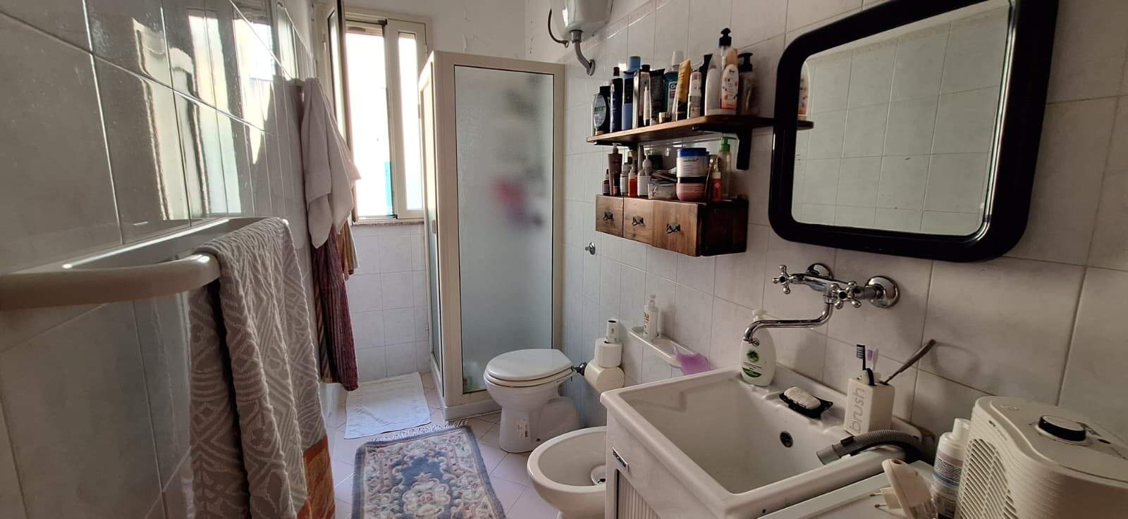 Lavabo e bagno con accessori, specchio e finestra, in un ambiente domestico.