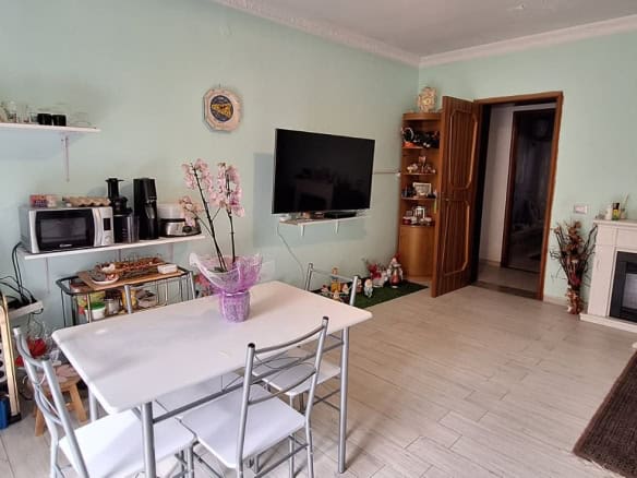 Ampia vista di un soggiorno luminoso con pareti verde menta, mobili moderni, televisore a schermo piatto e camino, ideale per vivere momenti di relax e convivialità in un ambiente accogliente.