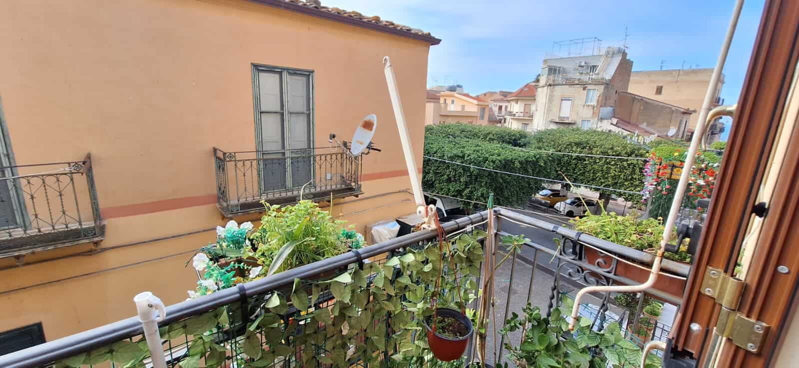 Balcone di un appartamento con piante e vista sulla città, in un contesto urbano italiano, con edifici storici e cielo sereno, ideale per chi cerca un angolo di relax all'aperto.