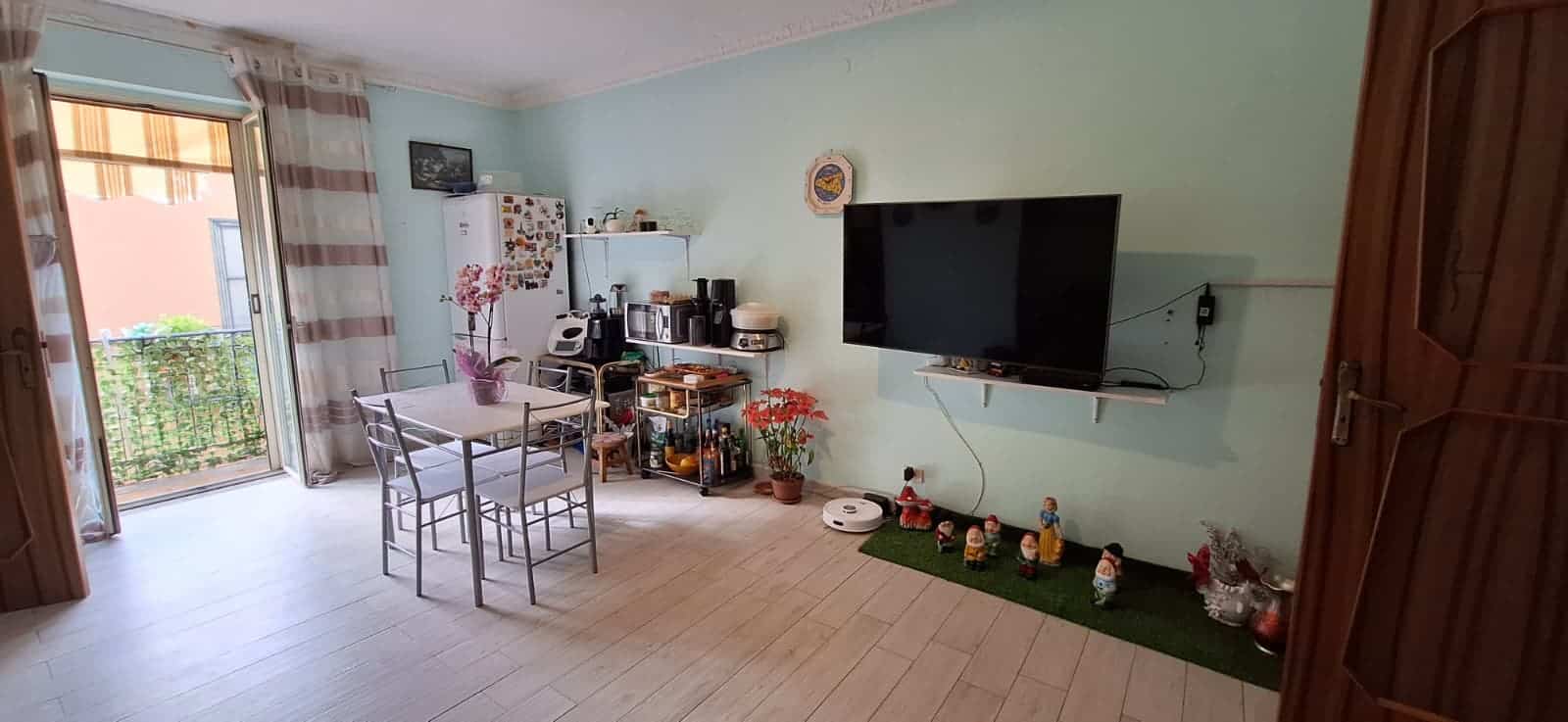 Appartamento luminoso con soggiorno e zona pranzo, TV a schermo piatto, decorazioni natalizie e accessori per la casa, con balcone che si affaccia su un cortile esterno.