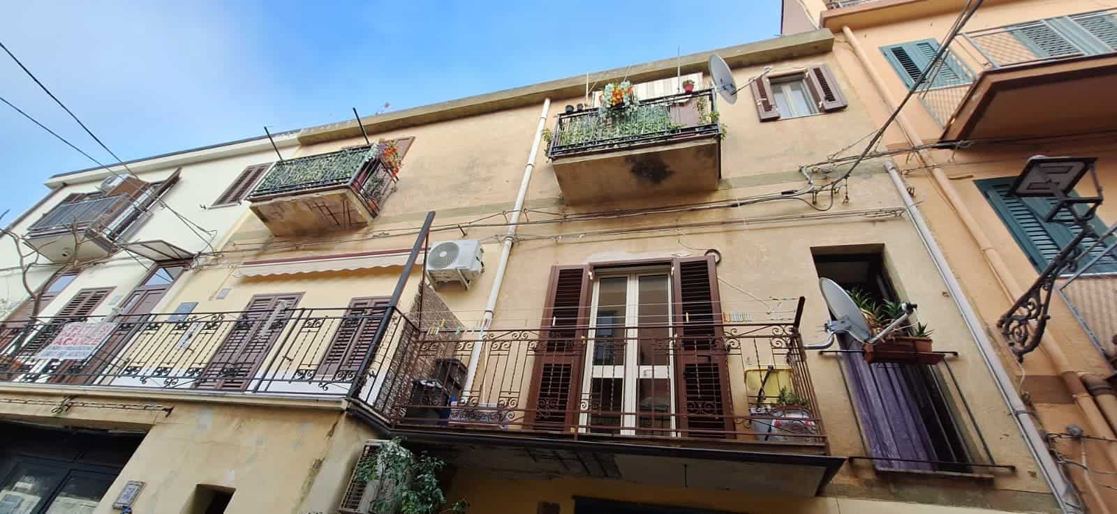 Scorcio di un edificio residenziale con balconi e finestre, in stile urbano italiano, con dettagli di piante e arredi esterni, ideale per chi cerca appartamenti in centro città.