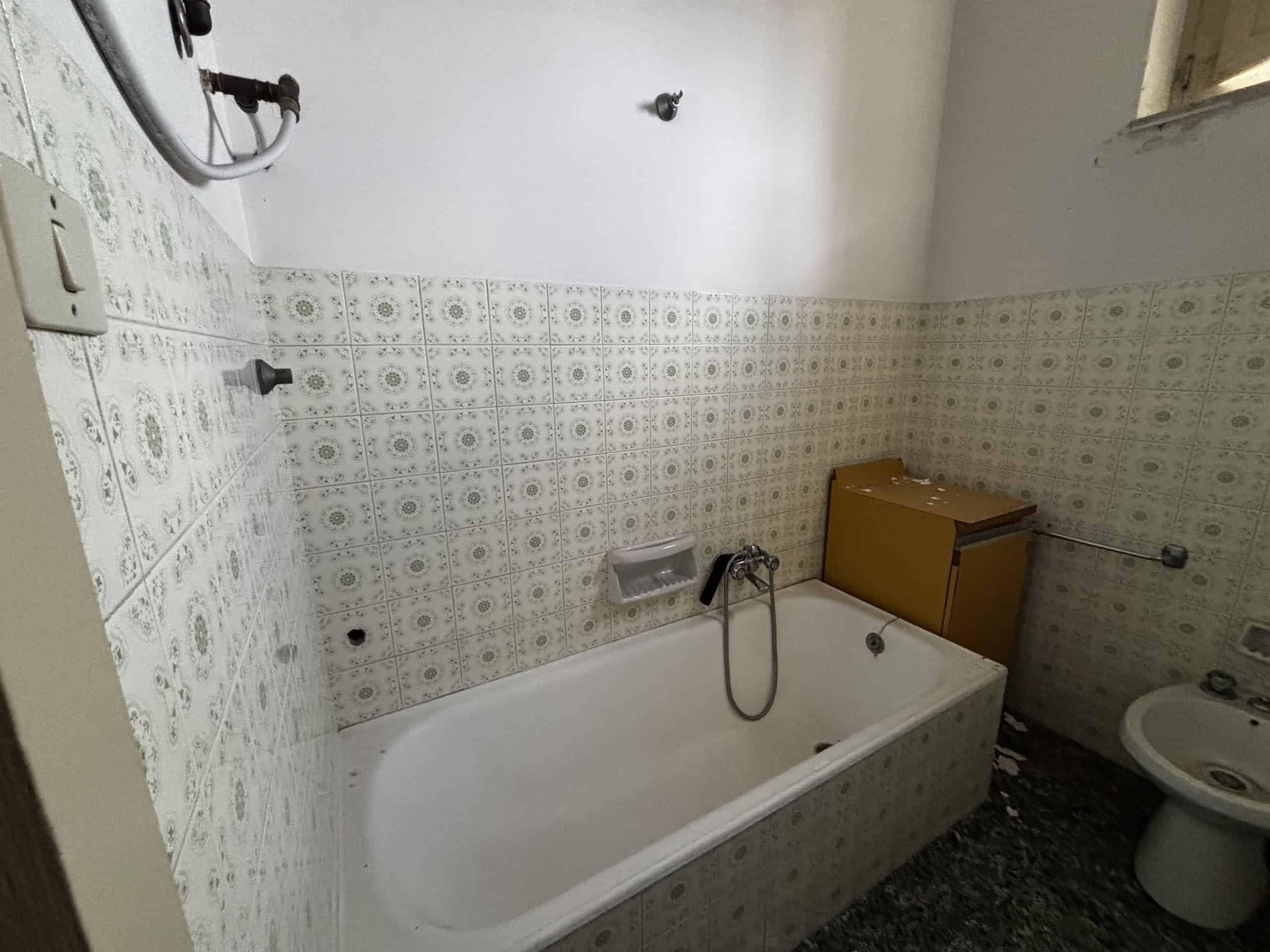 Doccia e vasca da bagno in un bagno ristrutturato con piastrelle decorative, lavabo e bidet, ambiente luminoso e funzionale, ideale per abitazioni moderne e confortevoli.