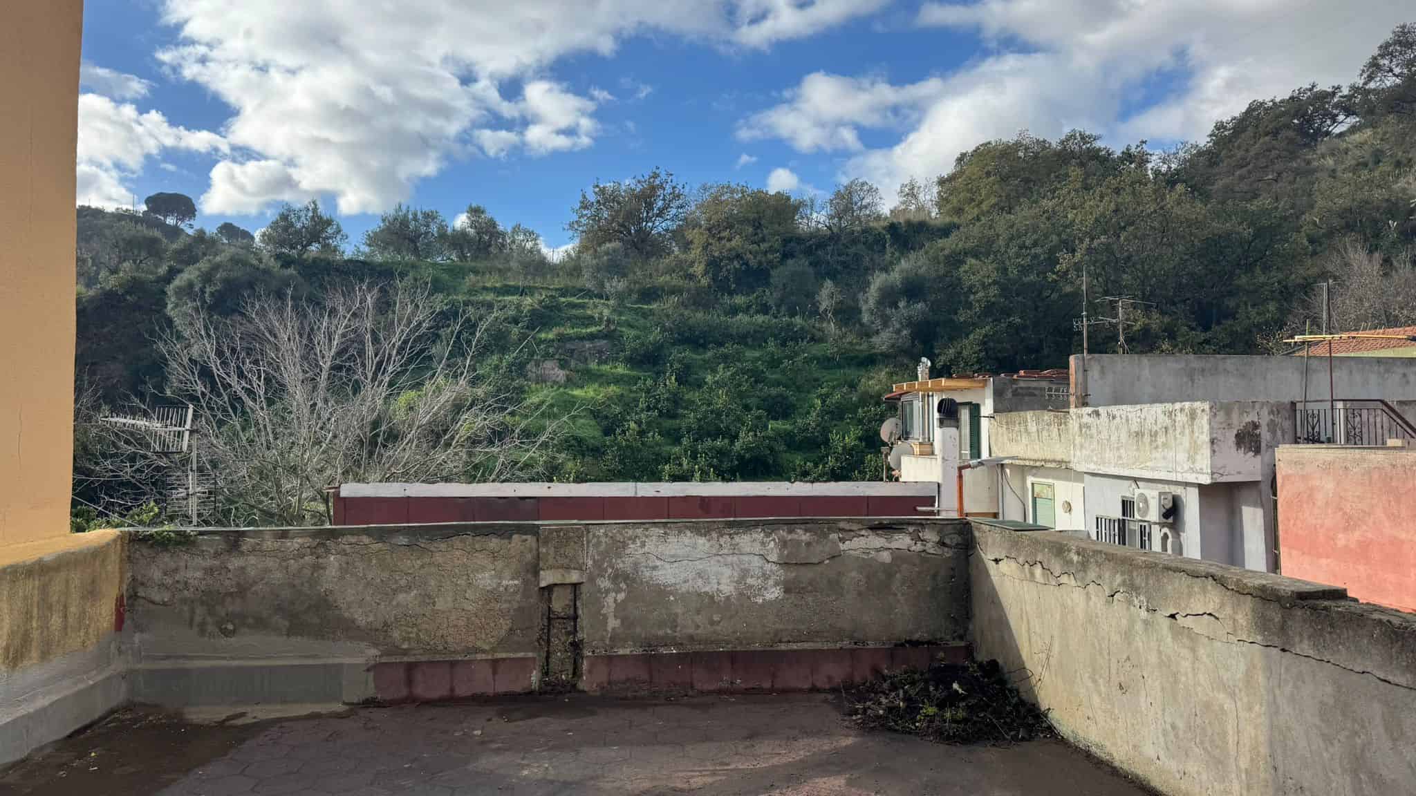 Balcone con vista su paesaggio collinare e cielo nuvoloso, in un contesto residenziale italiano, ideale per immobili e proprietà da valorizzare.