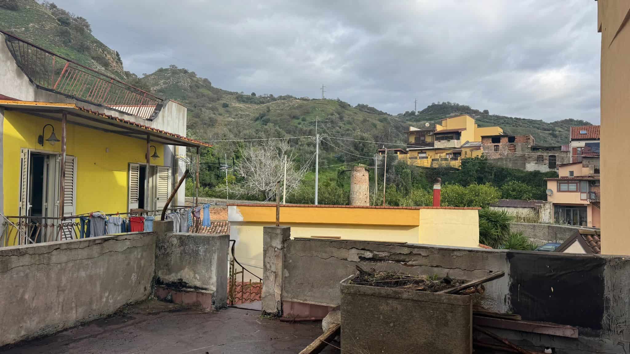 Scorcio di un terrazzo urbano con vista sulle colline e sui tetti delle case circostanti, in un contesto residenziale italiano.