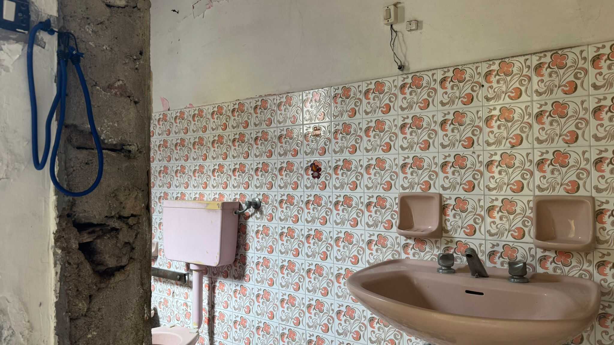 Lavandino da bagno con piastrelle decorative, dettagli di rubinetteria e pareti in fase di ristrutturazione, ambiente di casa in fase di rinnovamento.
