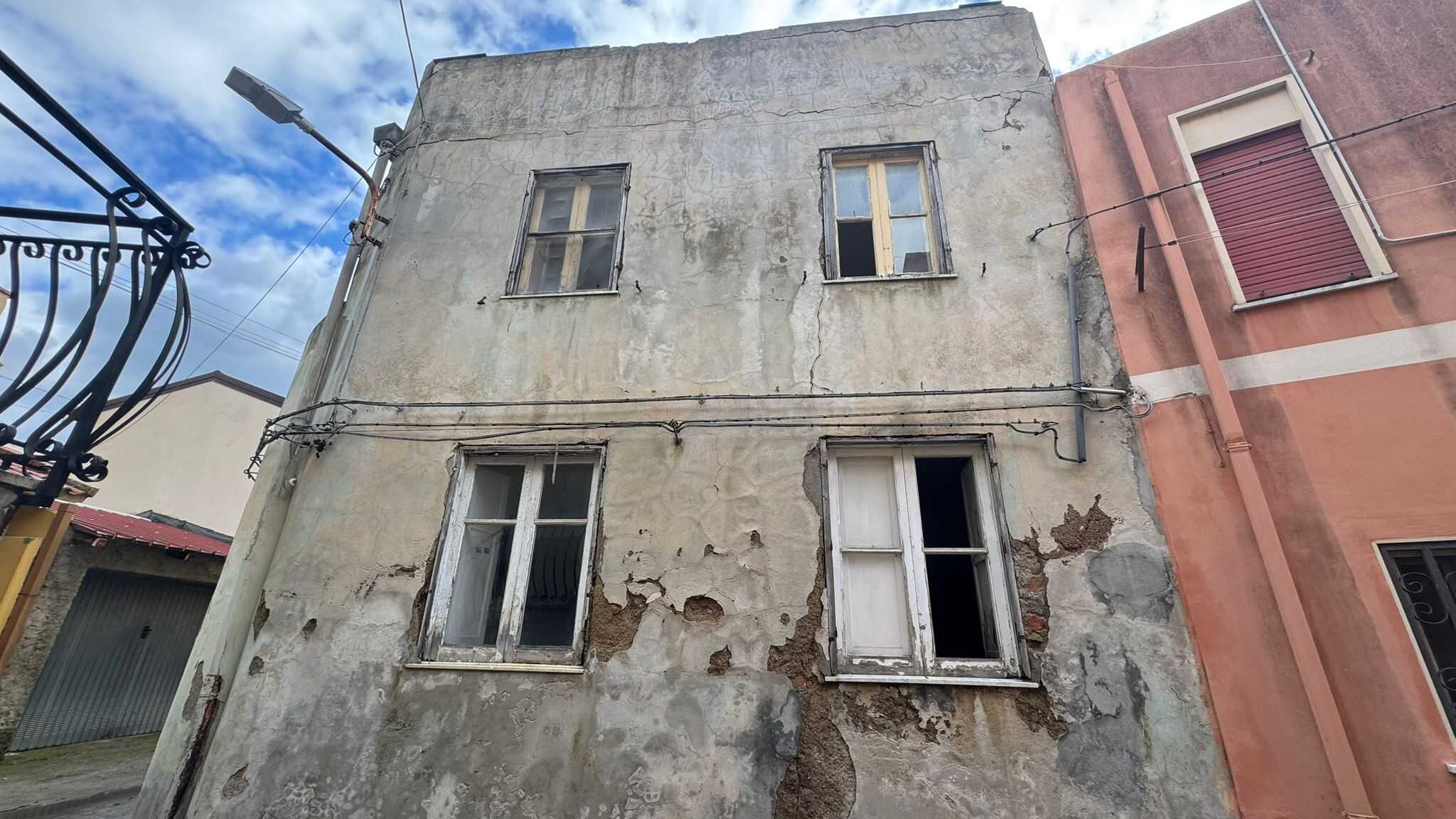 Vecchia casa in condizioni di degrado con pareti usurate e finestre danneggiate, pronta per ristrutturazione e riqualificazione nel mercato immobiliare.