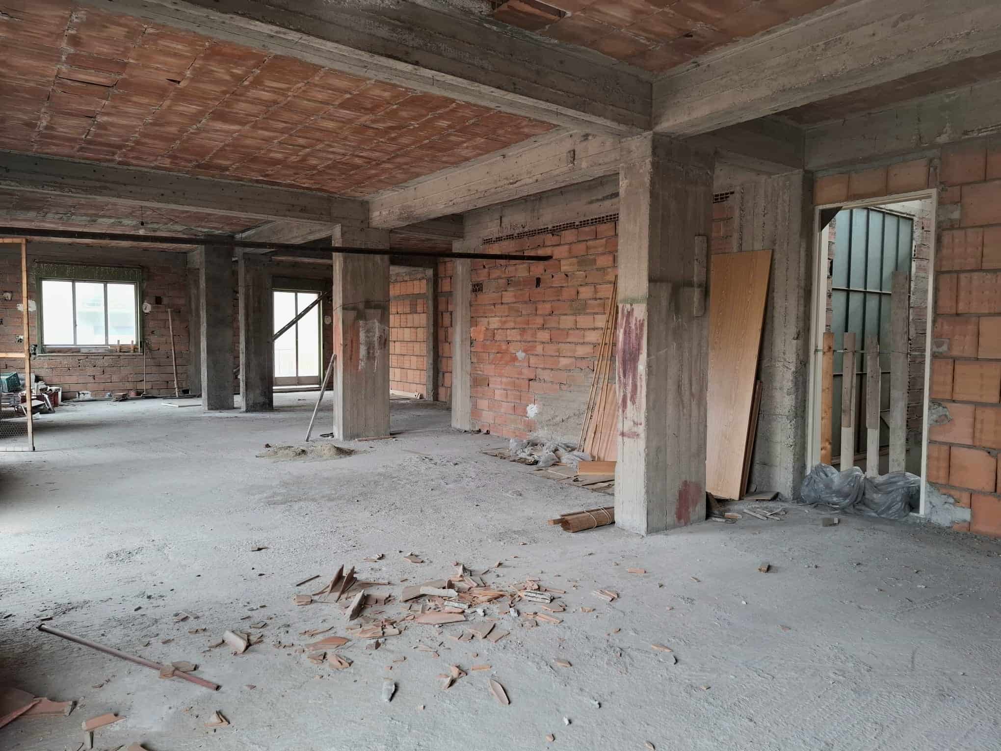 Interno di un edificio in costruzione con strutture in cemento e mattoni, pronto per finiture e rifiniture interne.