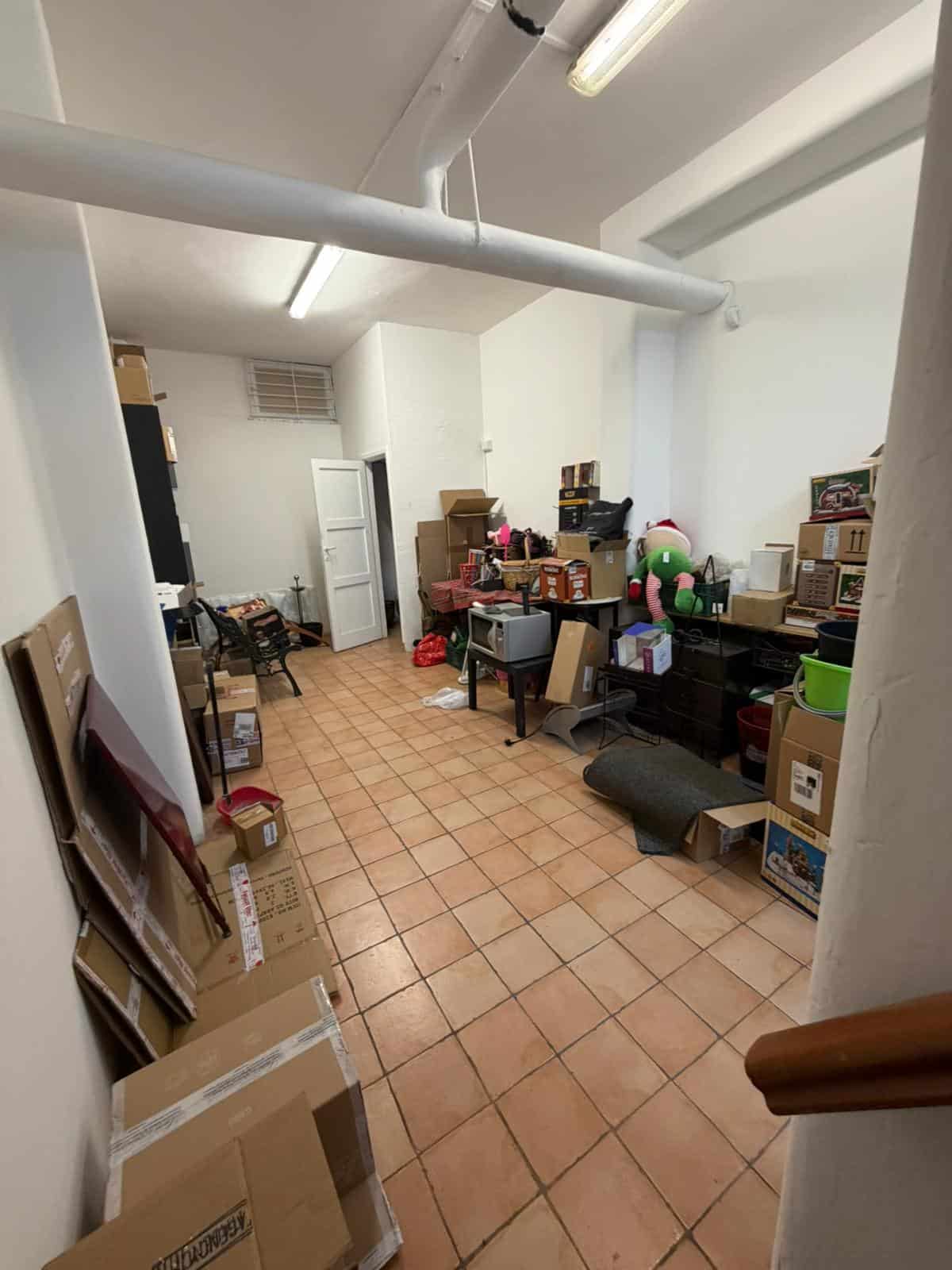 Scaffale e scatole di imballaggio in un magazzino o deposito, con oggetti vari e decorazioni natalizie, ambiente ordinato e funzionale per stoccaggio e organizzazione.