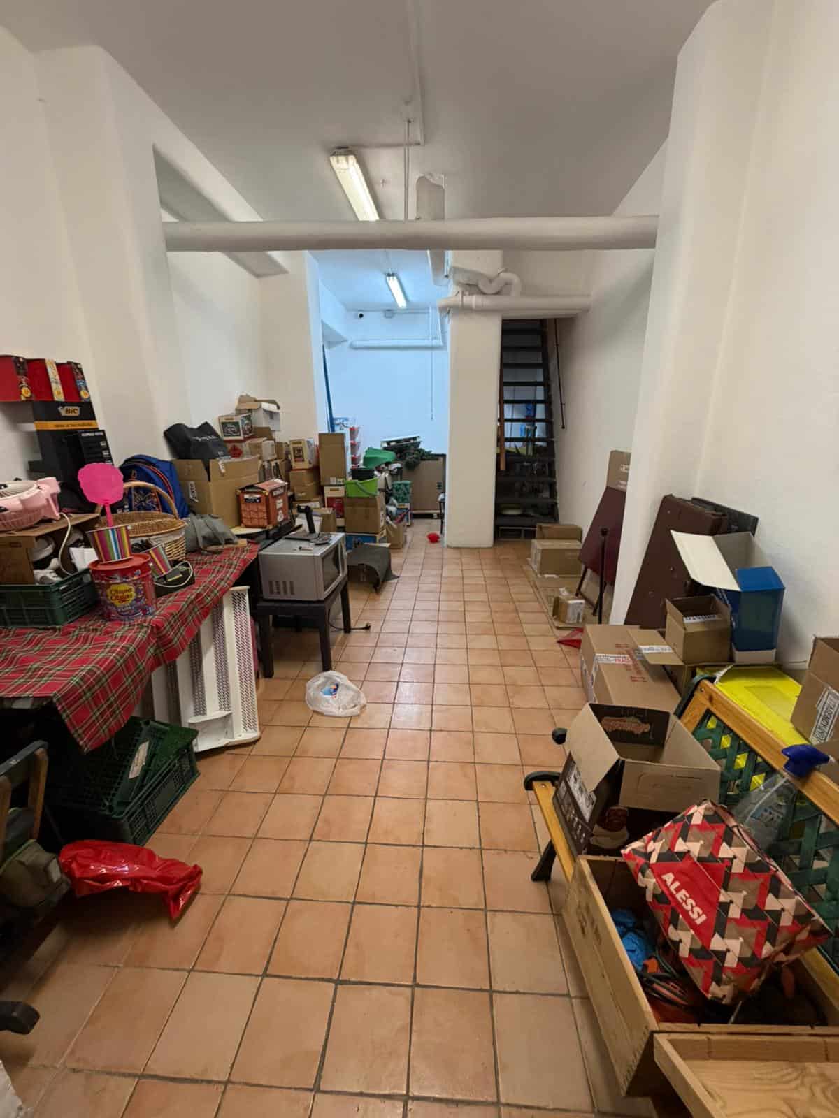 Spazio di magazzino con scaffali, scatole e oggetti vari, ambiente luminoso e ben organizzato.