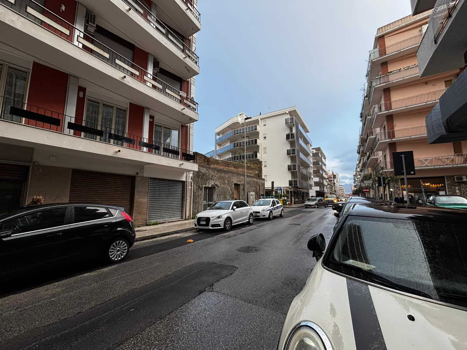 Auto in strada con edifici residenziali moderni sullo sfondo, cielo sereno, atmosfera urbana vivace e dinamica, parcheggio pubblico, dettagli architettonici contemporanei, ambiente cittadino, vista pa.