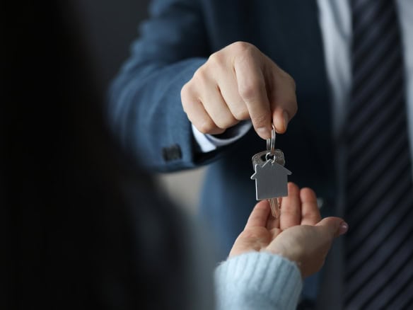 Vendita di casa con chiavi in mano, agente immobiliare consegna le chiavi a un cliente, immagine di un accordo immobiliare, servizio di intermediazione immobiliare, concetto di compravendita immobilia.
