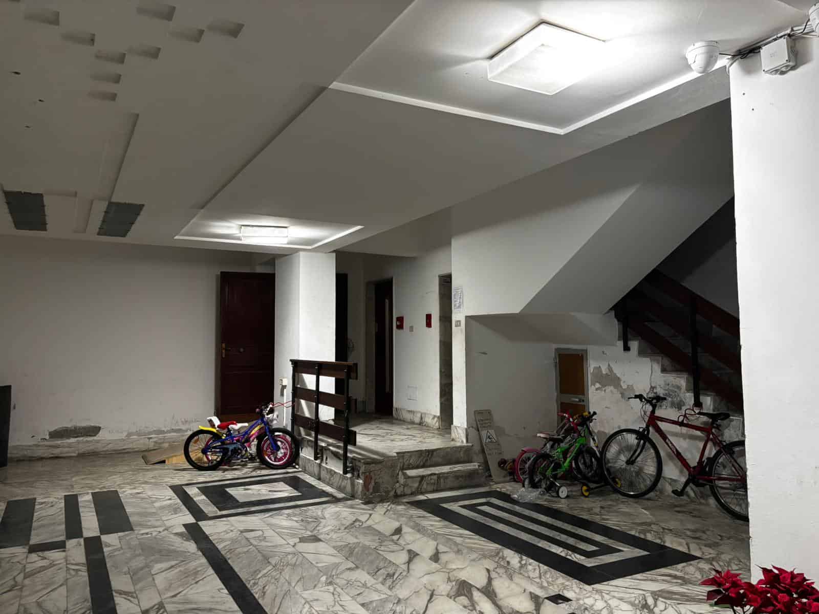 Pannelli di biciclette e spazio di ingresso in un condominio moderno con pavimento in marmo e pareti bianche.