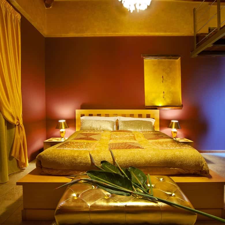 Luminosa camera da letto con pareti colorate, grande letto matrimoniale, armadio in legno e decorazioni eleganti, ideale per soggiorni confortevoli e rilassanti.