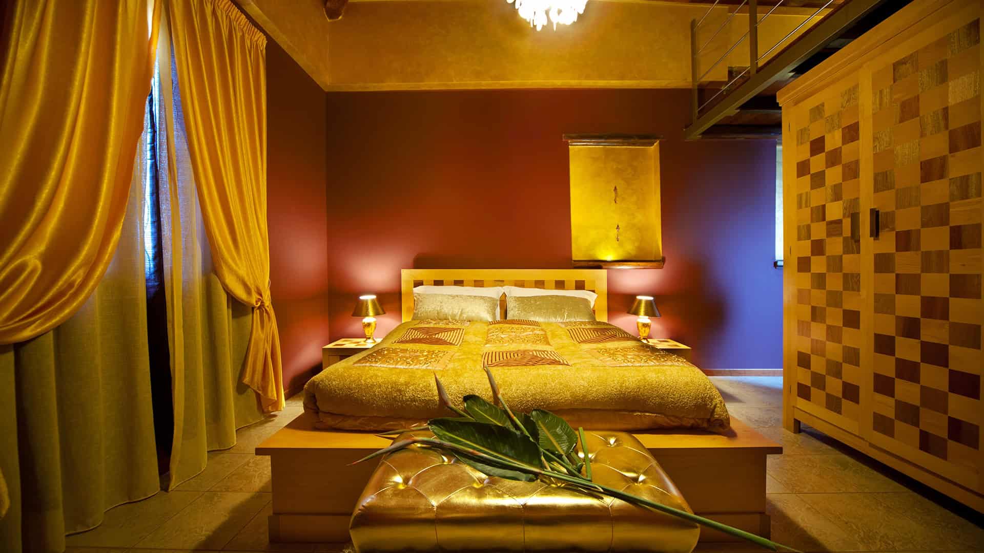 Luminosa camera da letto con pareti colorate, grande letto matrimoniale, armadio in legno e decorazioni eleganti, ideale per soggiorni confortevoli e rilassanti.