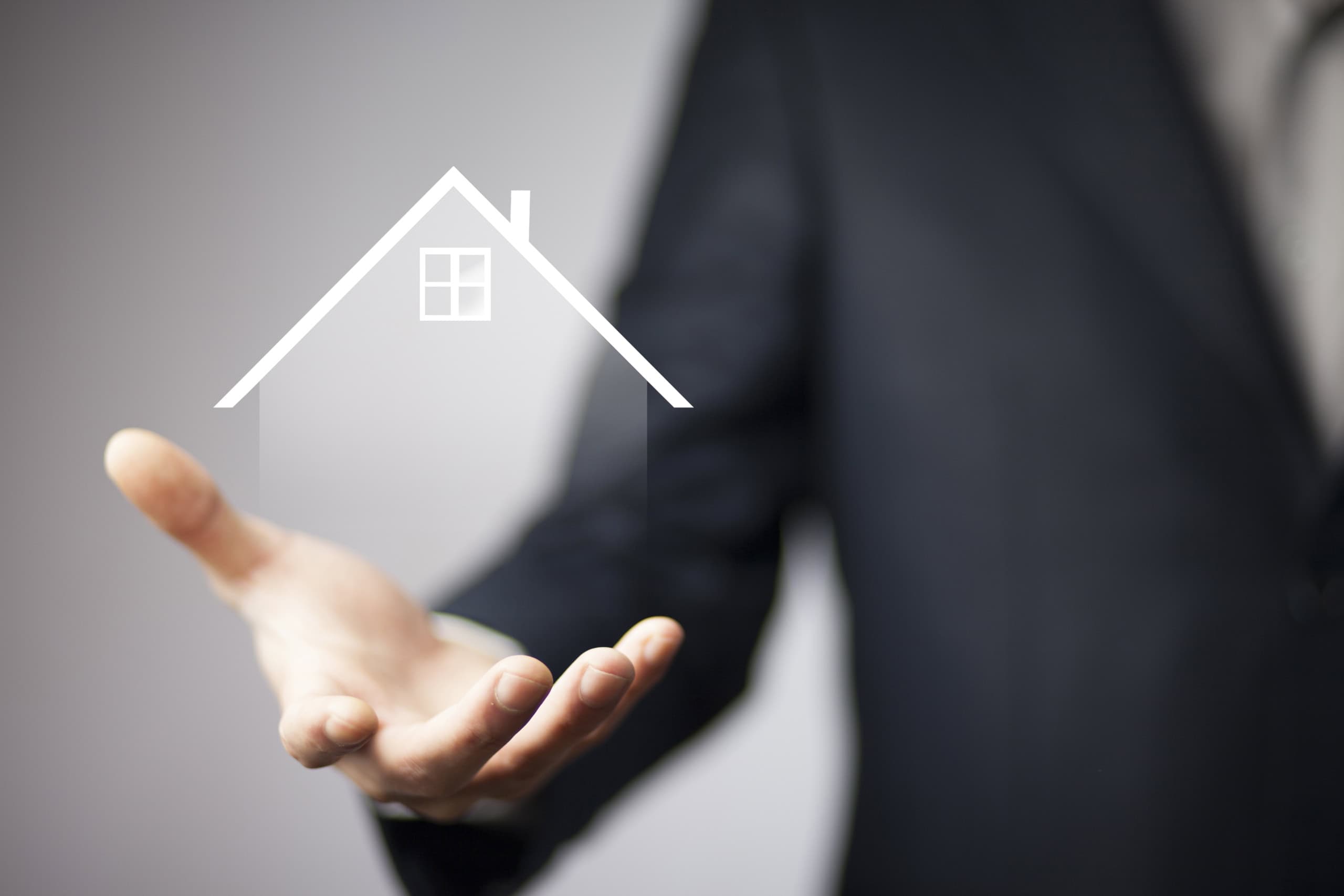 Immagine di un professionista che tiene in mano un'icona di una casa stilizzata, simbolo di servizi immobiliari e consulenza abitativa.