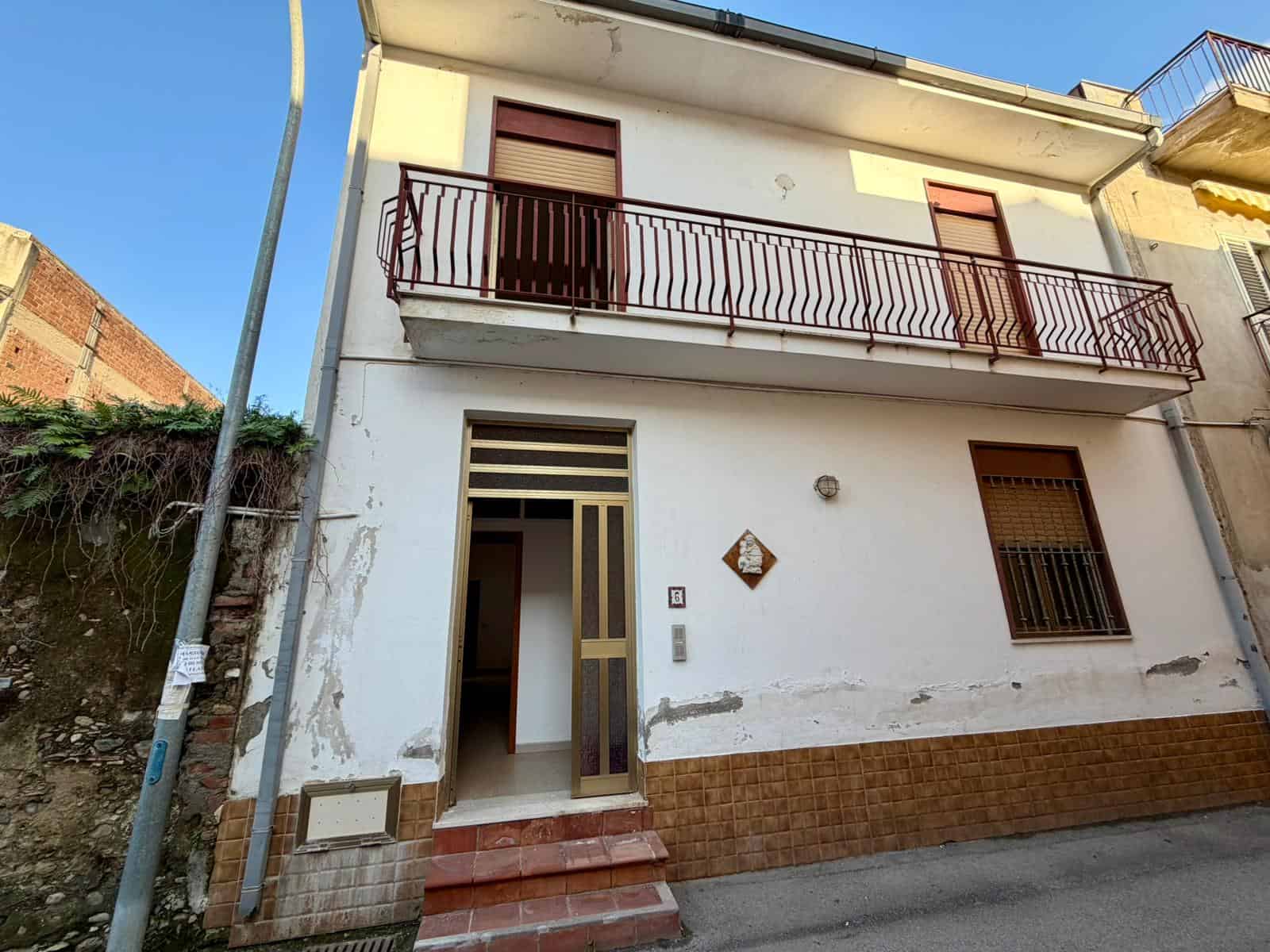 Casa indipendente con balcone e ingresso principale in zona residenziale.