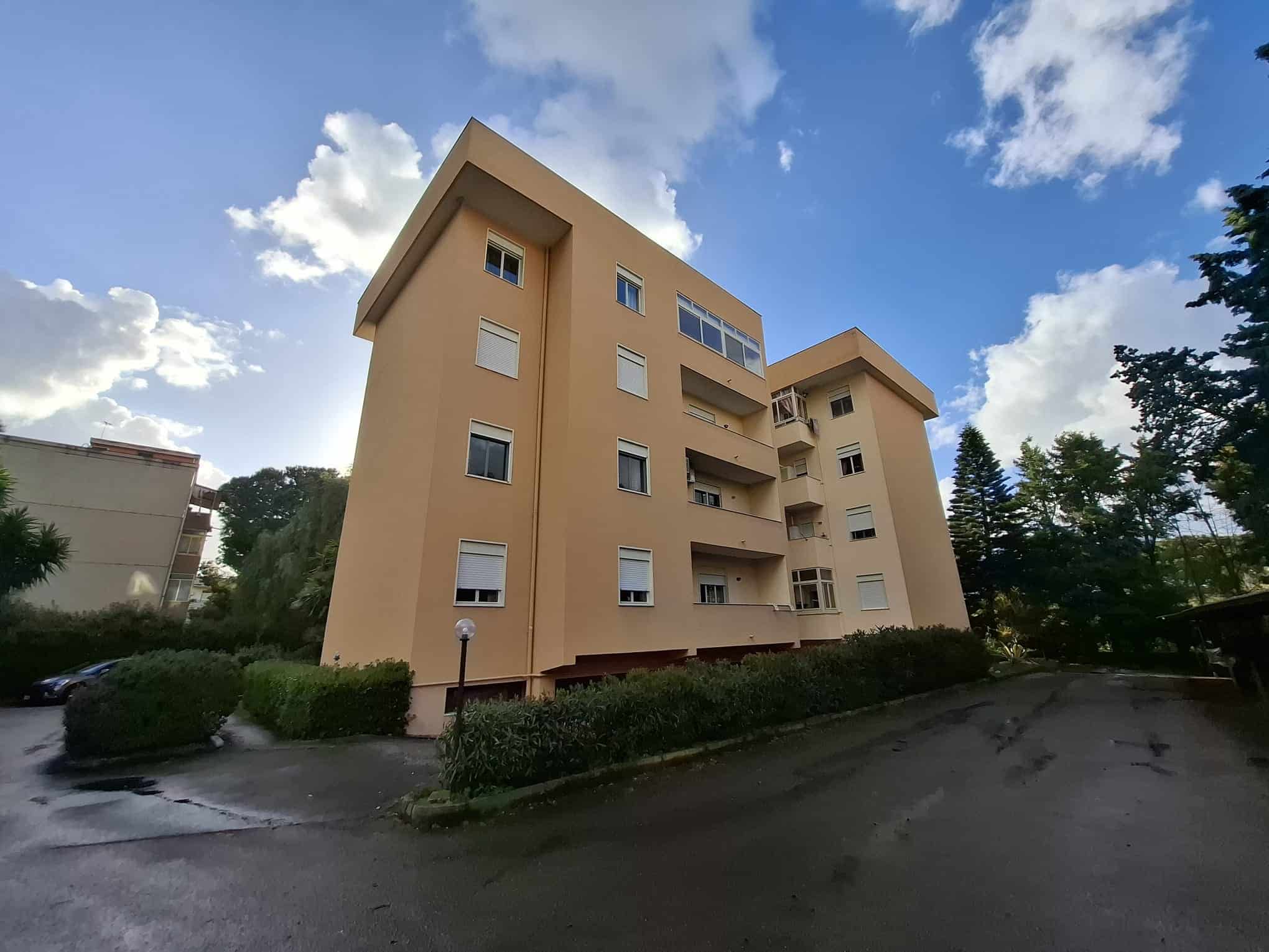Appartamento in edificio residenziale con balconi e grandi finestre, situato in un'area tranquilla circondata da alberi e natura, ideale per vivere in tranquillità e comfort.